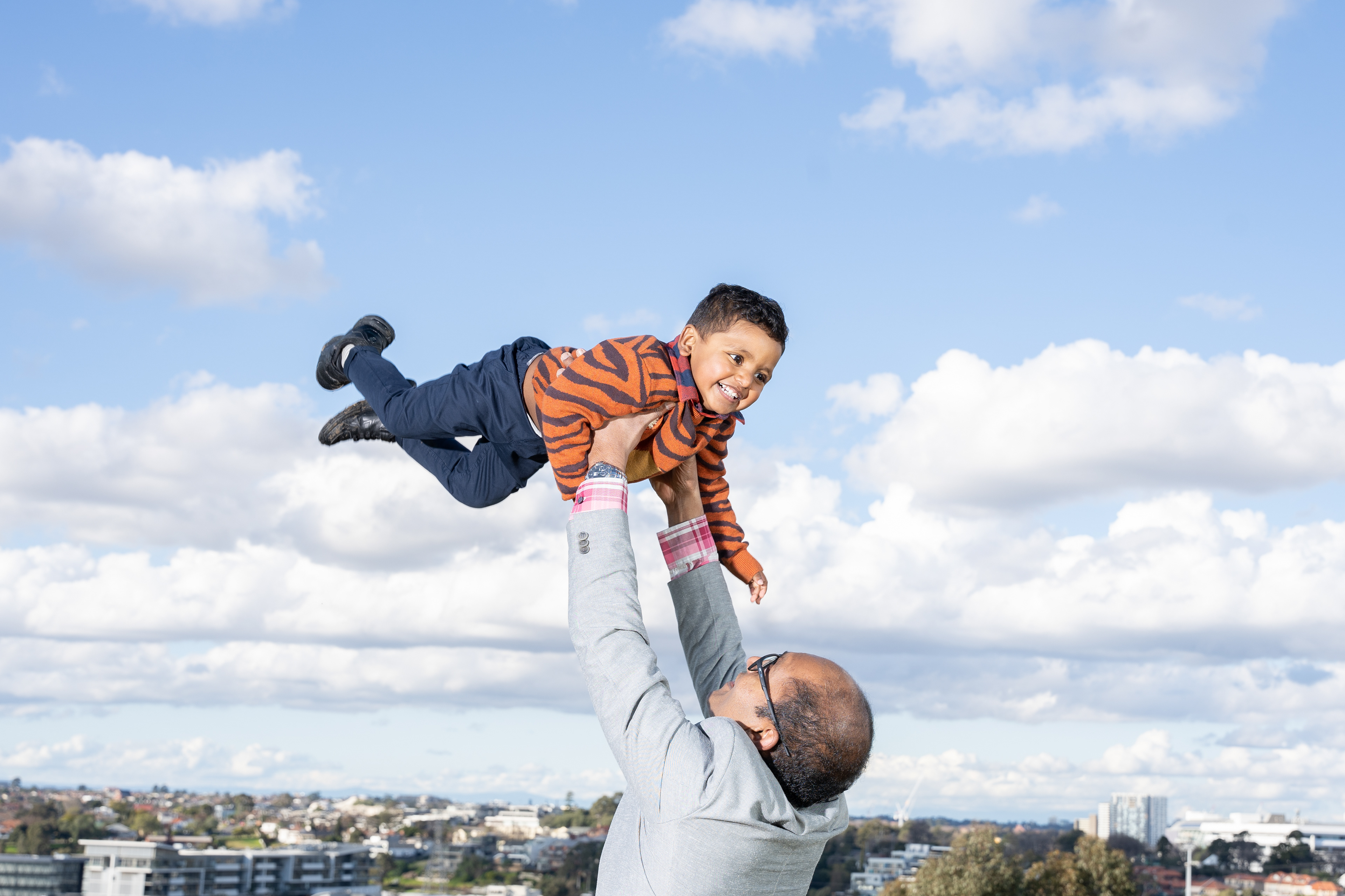 Parent lifting a child against an open sky