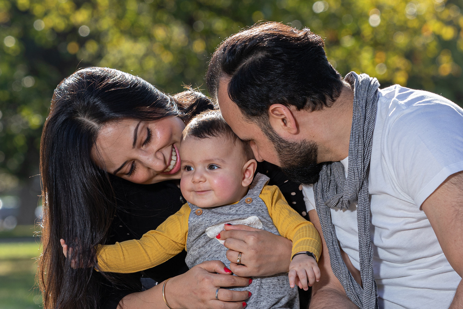 Parents leaning towards their baby outdoors