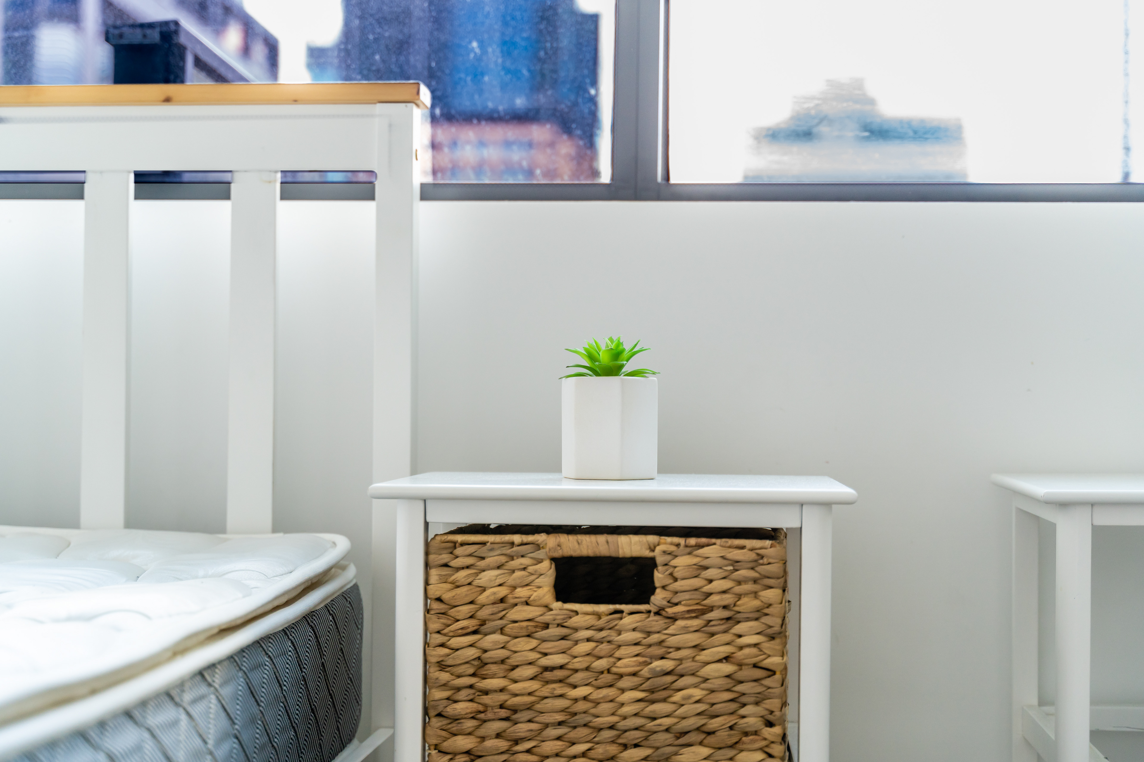 Bedside table with a small plant beside a bedroom window