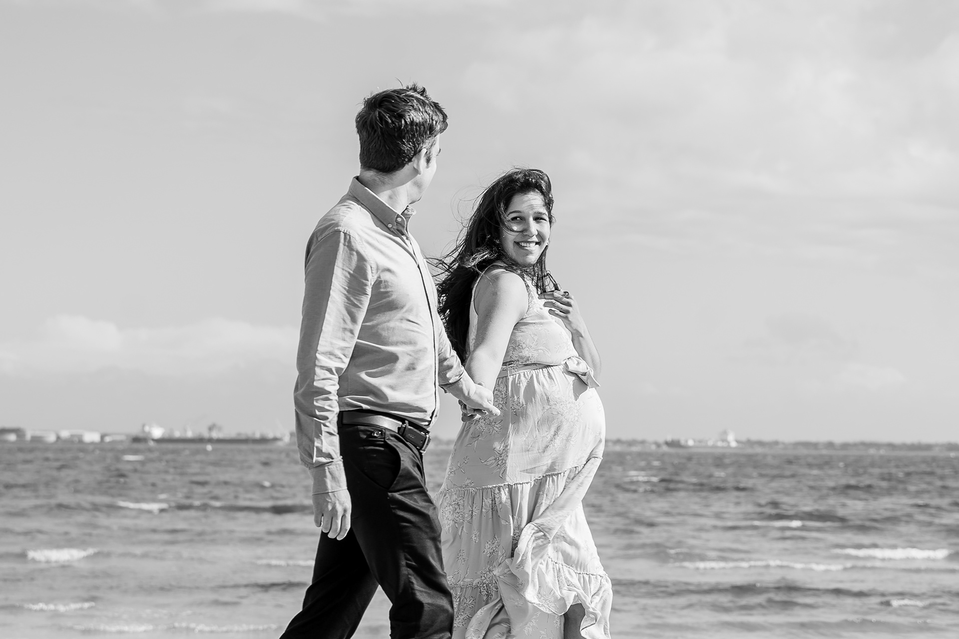 Black-and-white portrait of a couple walking along the beach
