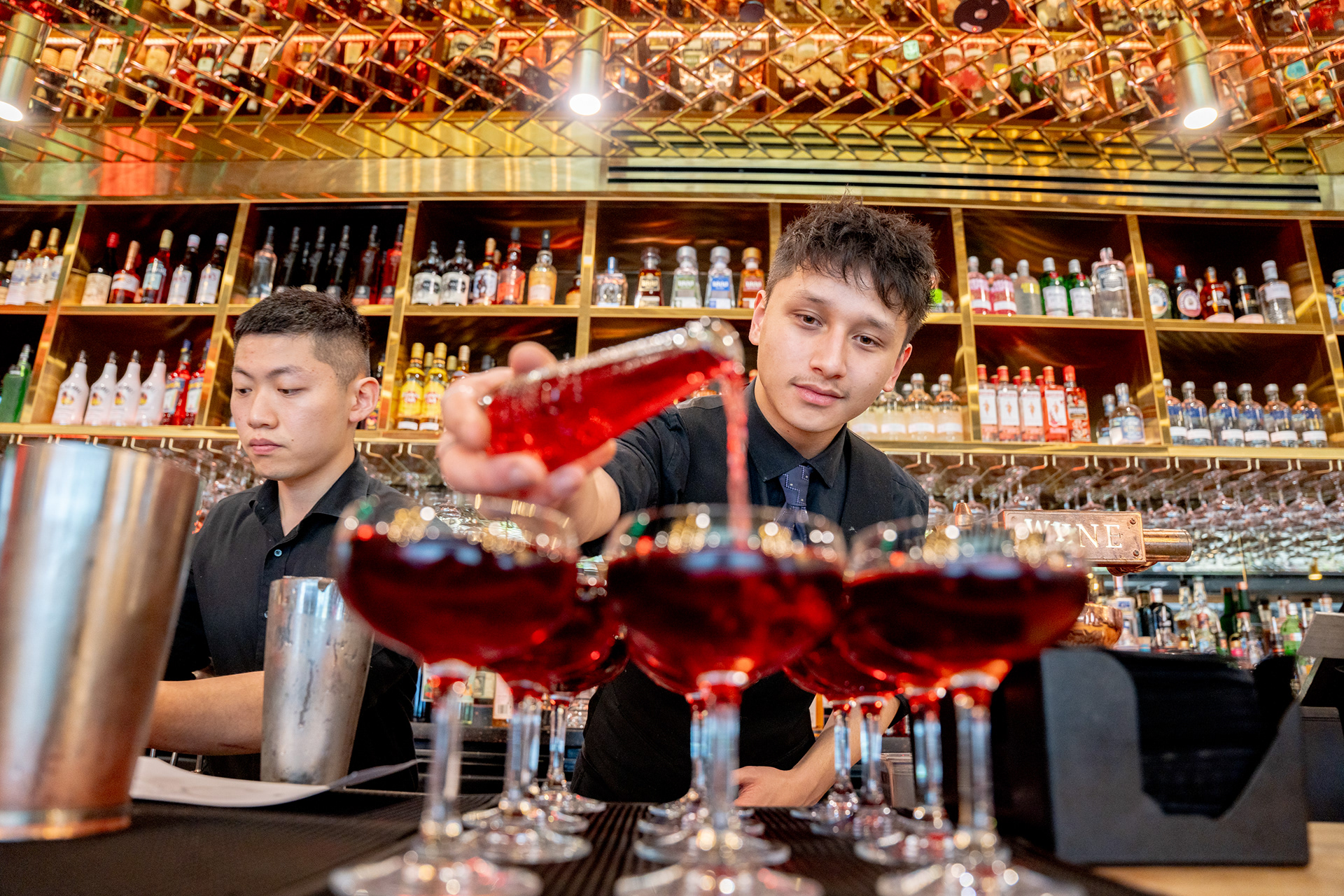 Bartender presenting a red cocktail across the bar