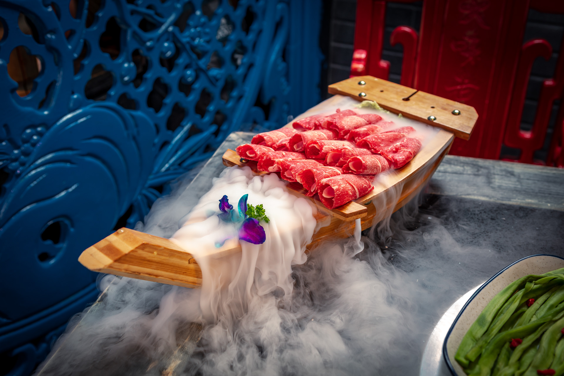 Marbled raw beef displayed on a wooden board with smoke