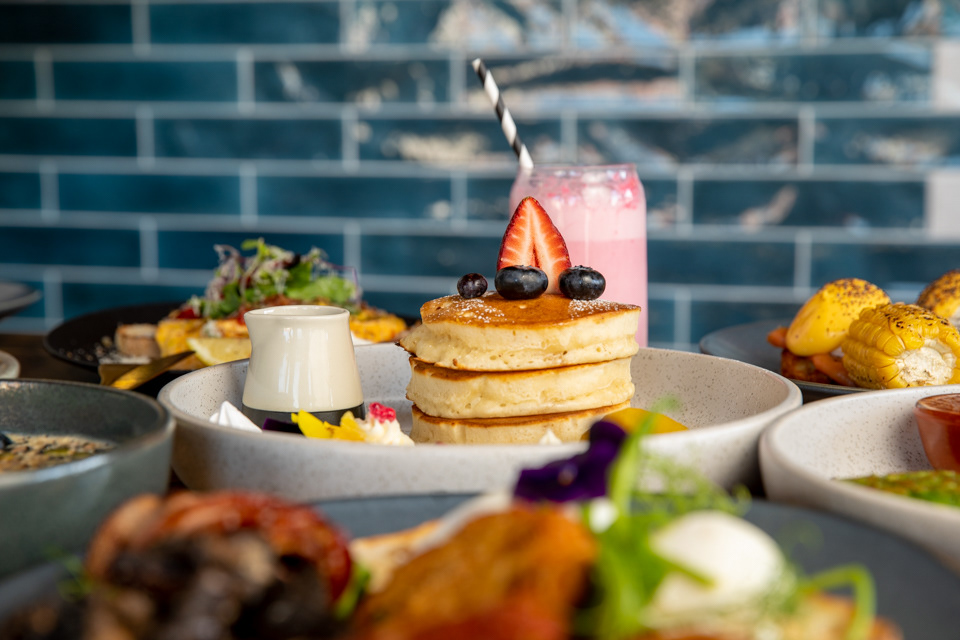 Syrup being poured over a stack of pancakes