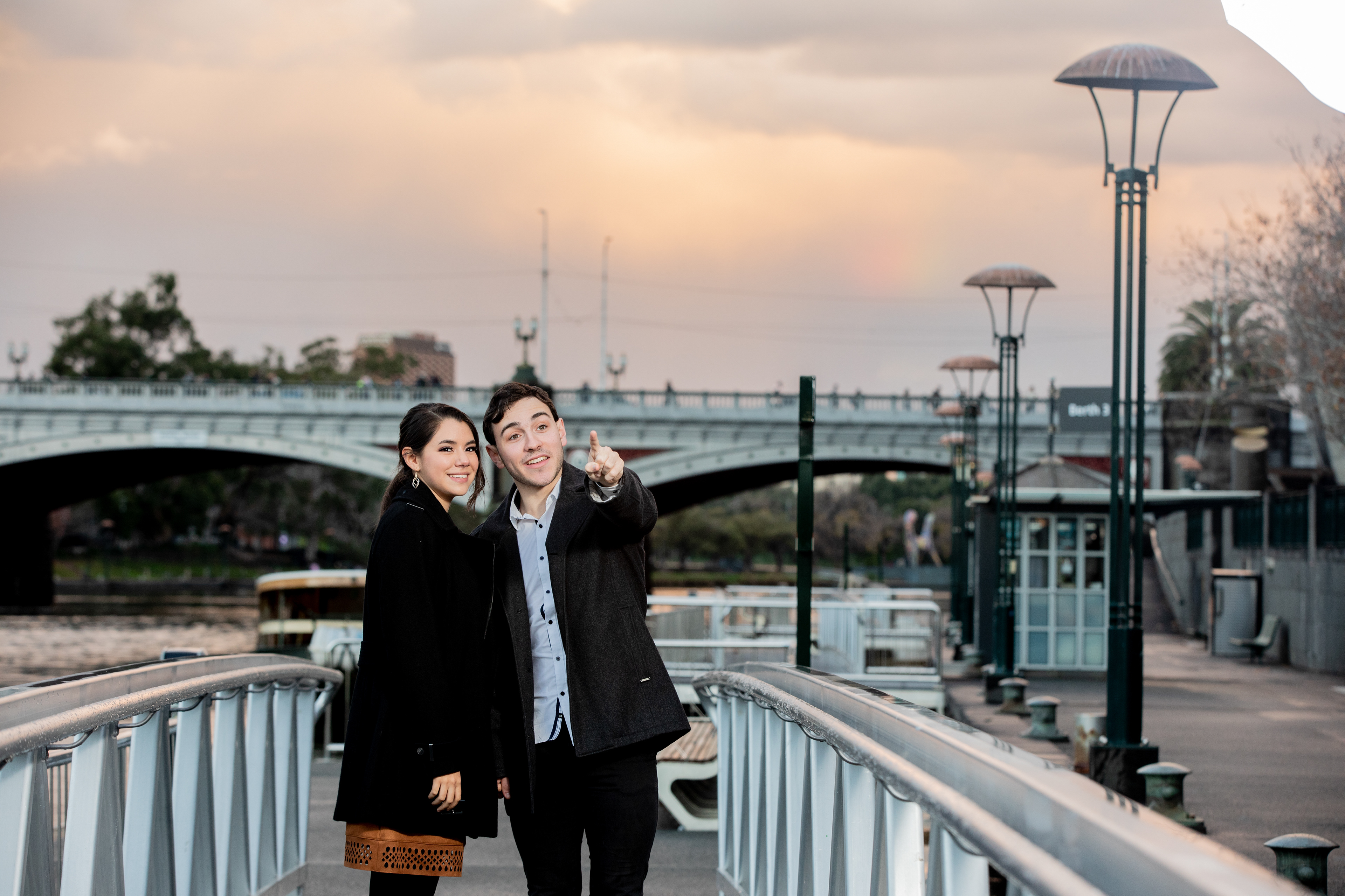 Couple embracing on a pedestrian bridge at sunset