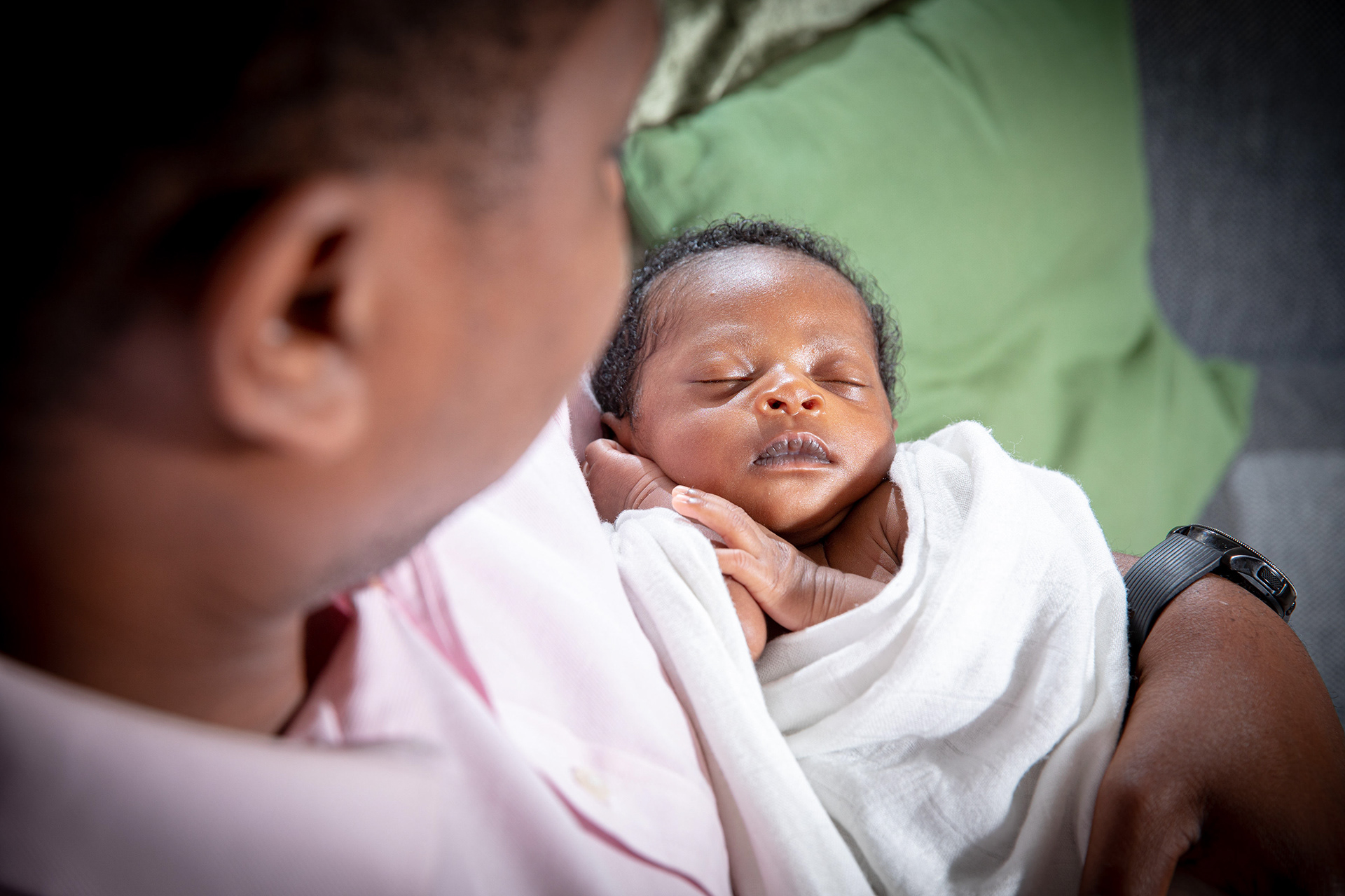 Close-up of a newborn cradled in a parent’s arms