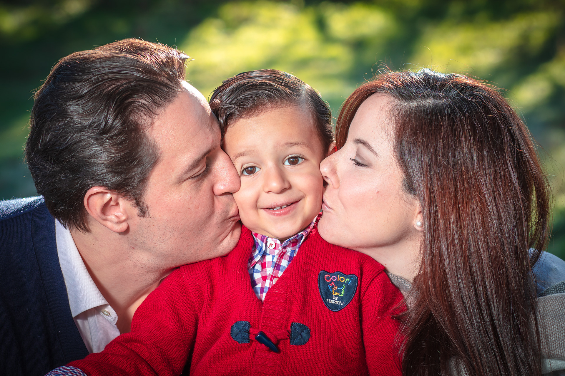 Parents kissing their child on both cheeks