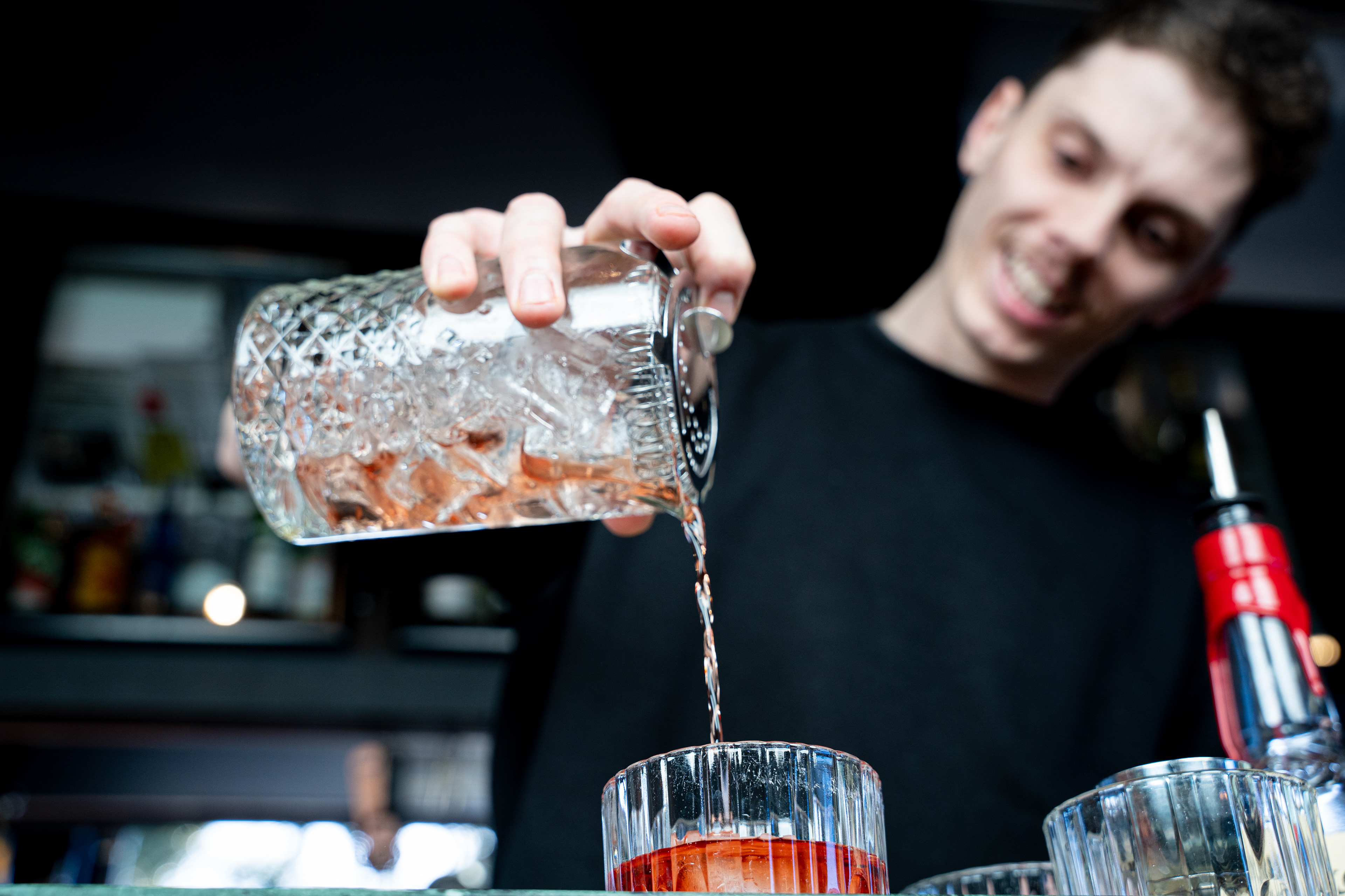 Bartender pouring a drink from a glass bottle