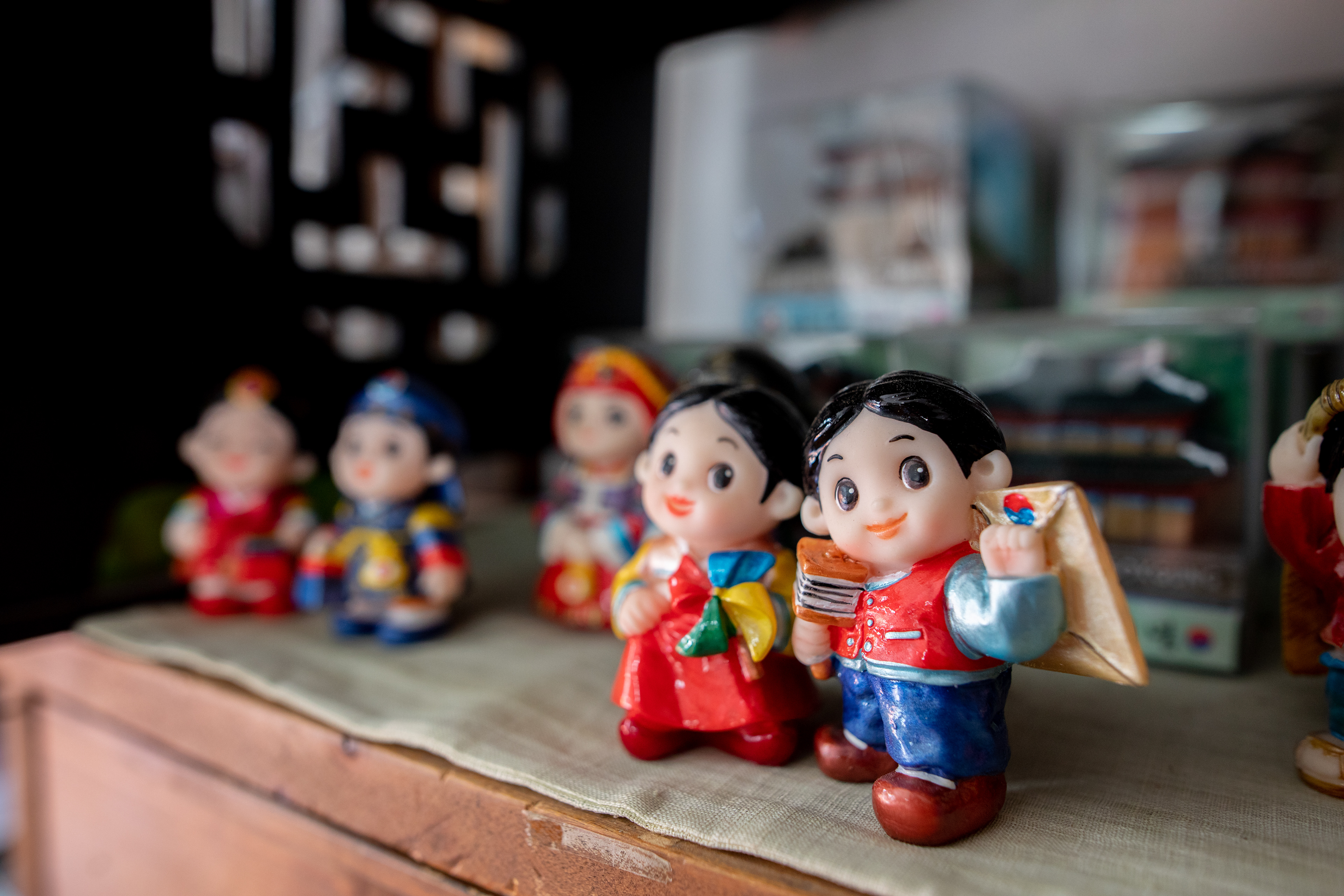 Small painted figures displayed on a wooden shelf