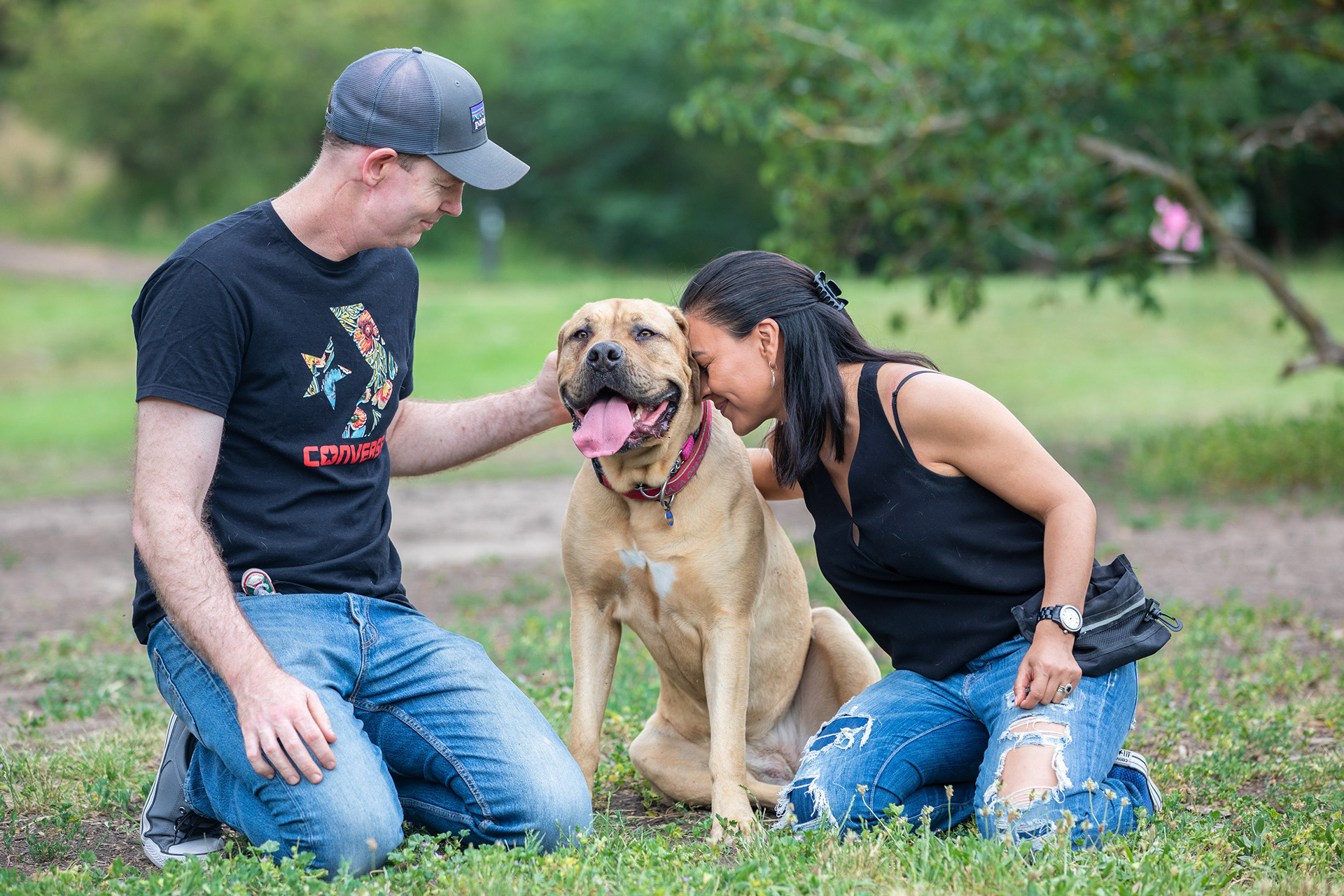 Couple kneeling beside their dog outdoors