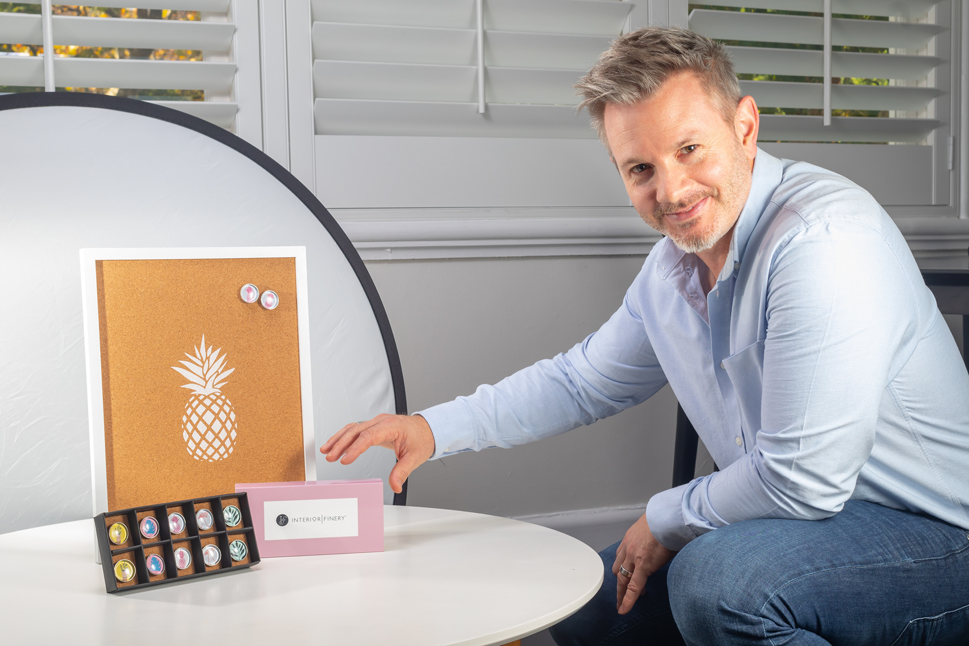 Personal branding portrait seated beside products and a photography reflector