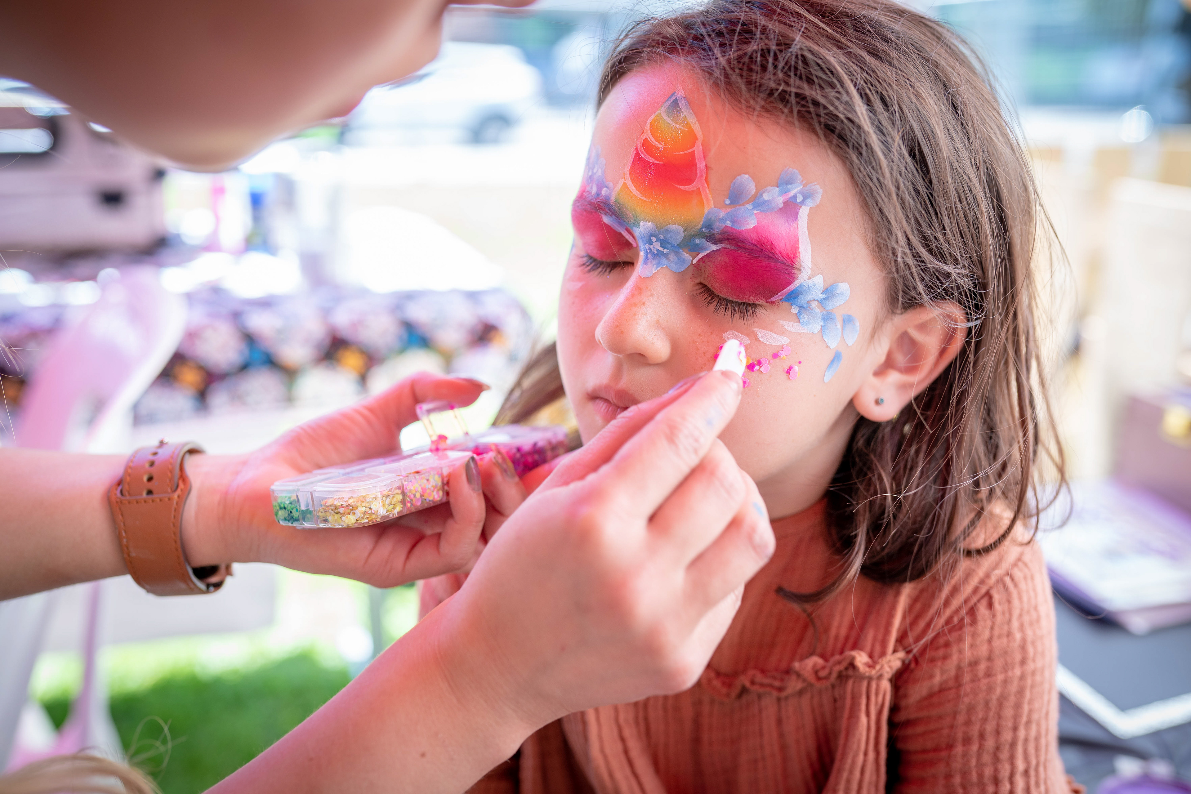 Child having colourful face paint applied at a party