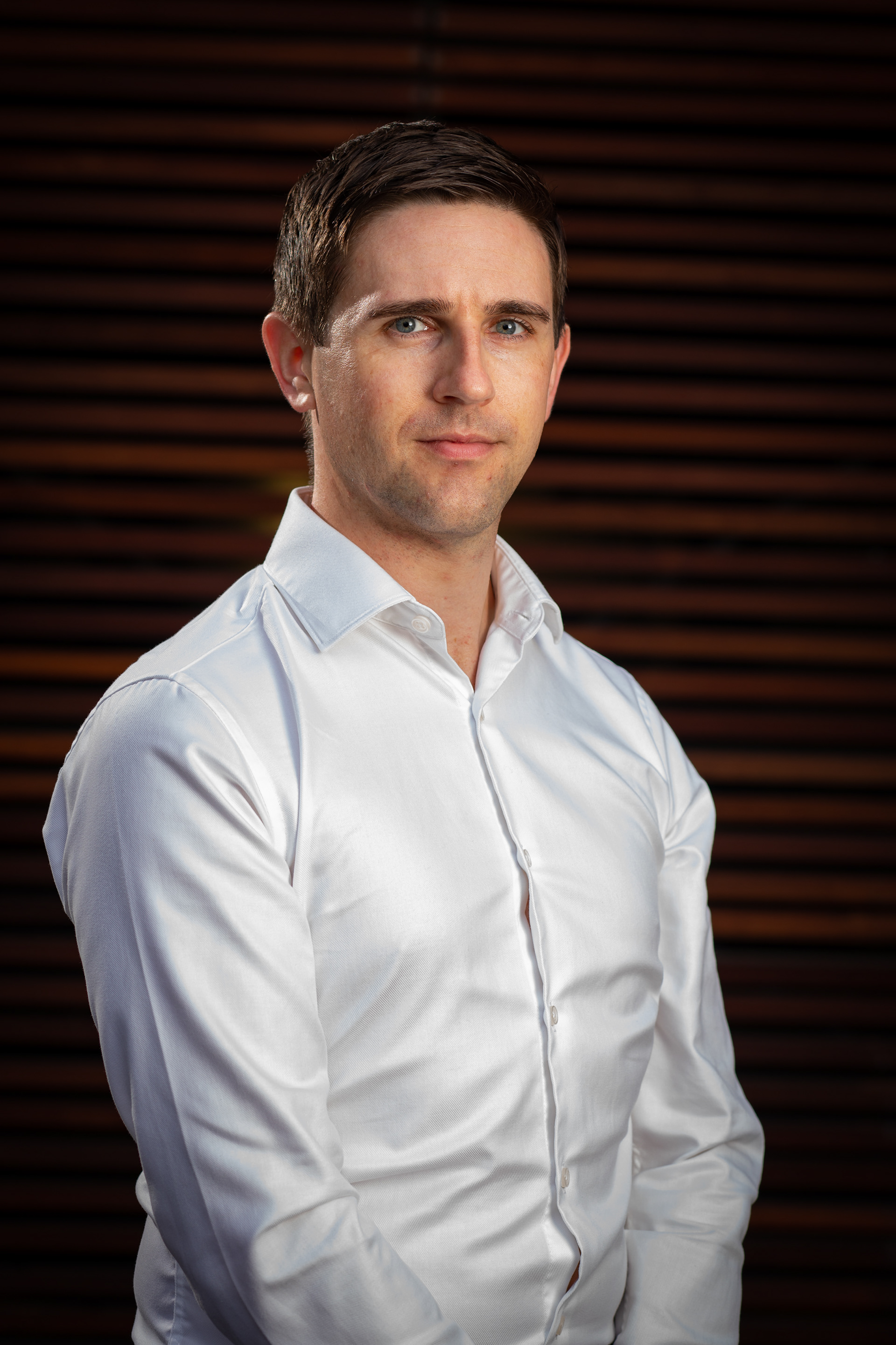 Portrait in a light shirt beside horizontal blinds