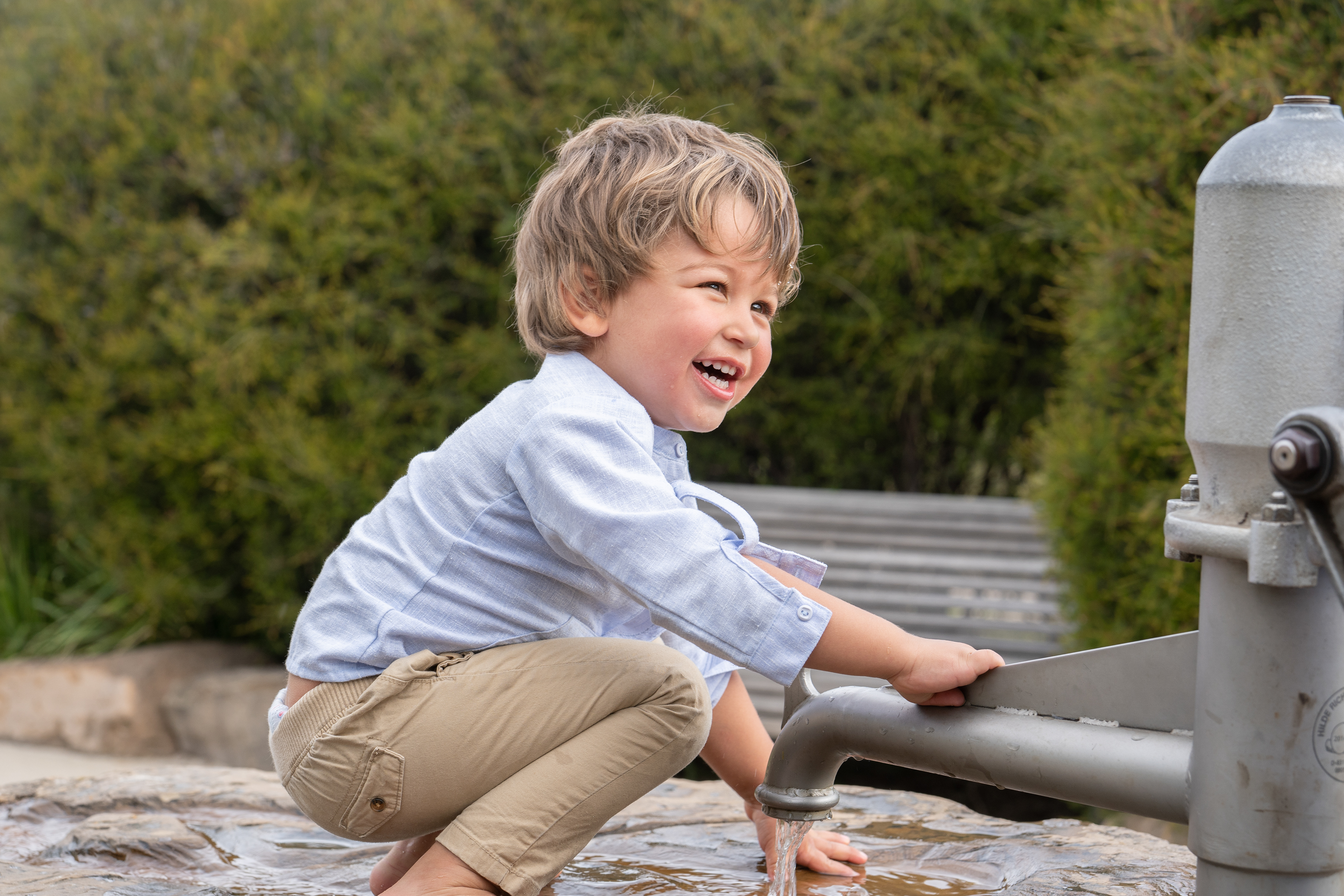Child playing with an outdoor water pump