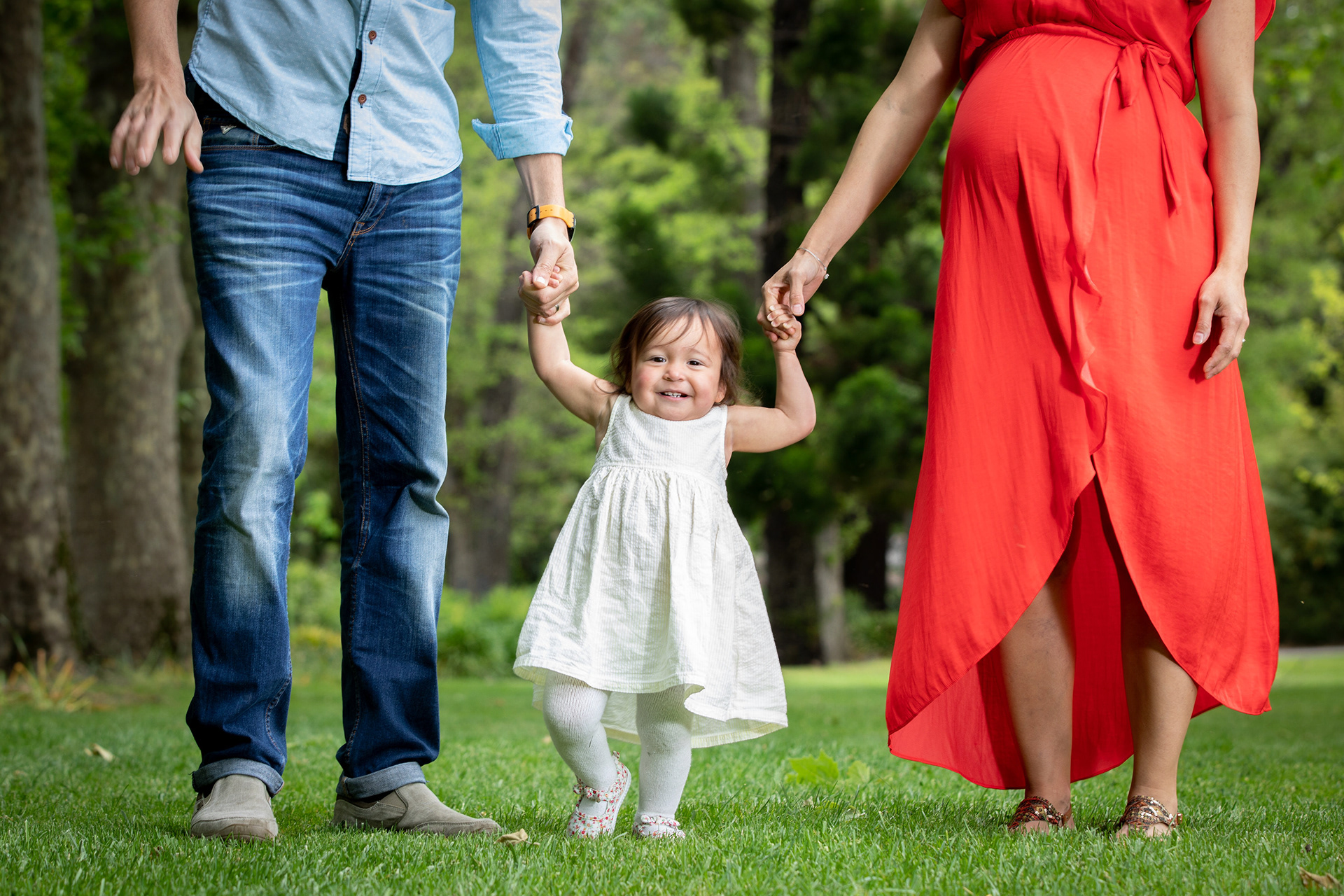 Toddler taking steps while holding parents’ hands