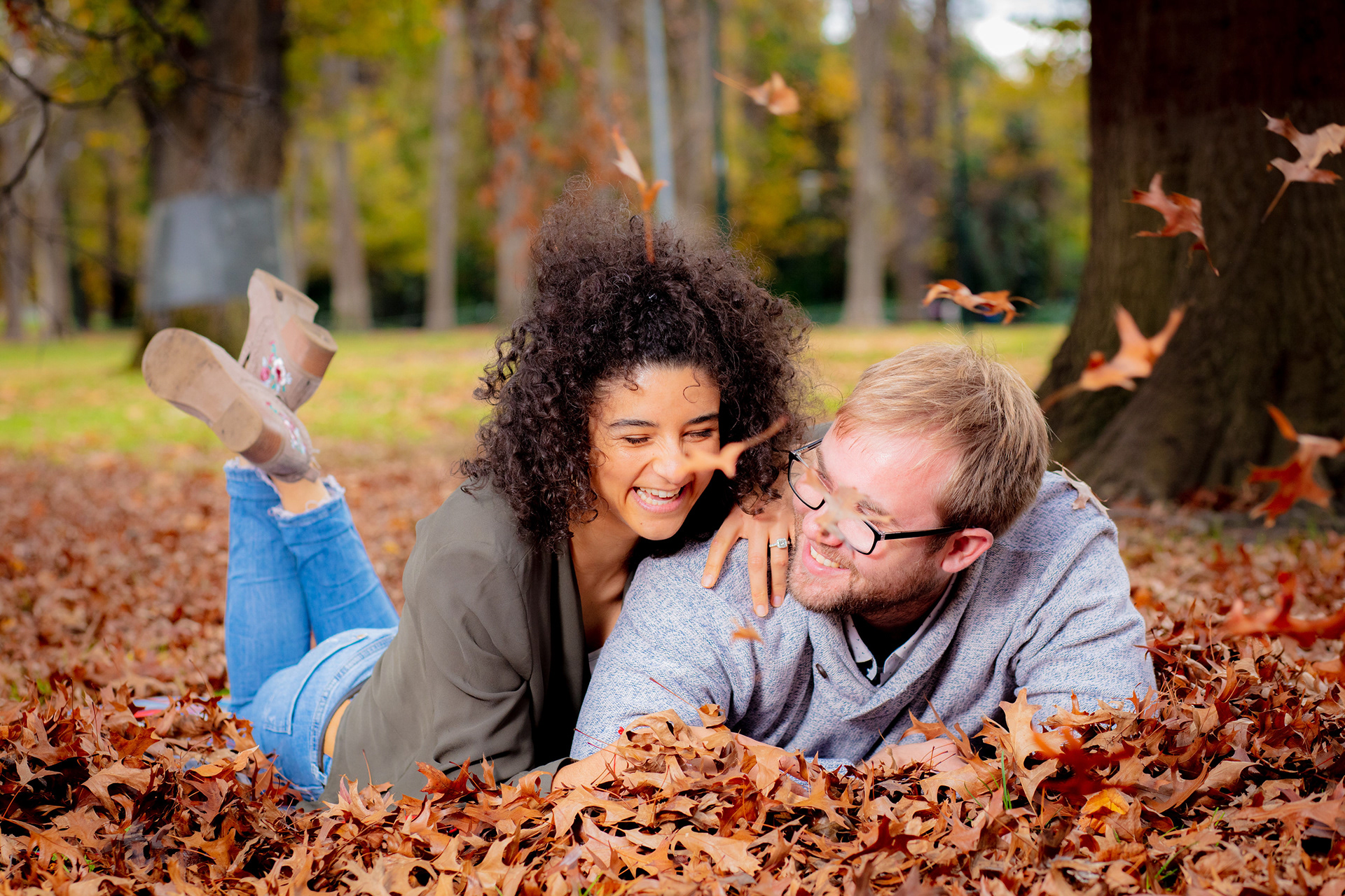 Couple laughing while lying in autumn leaves