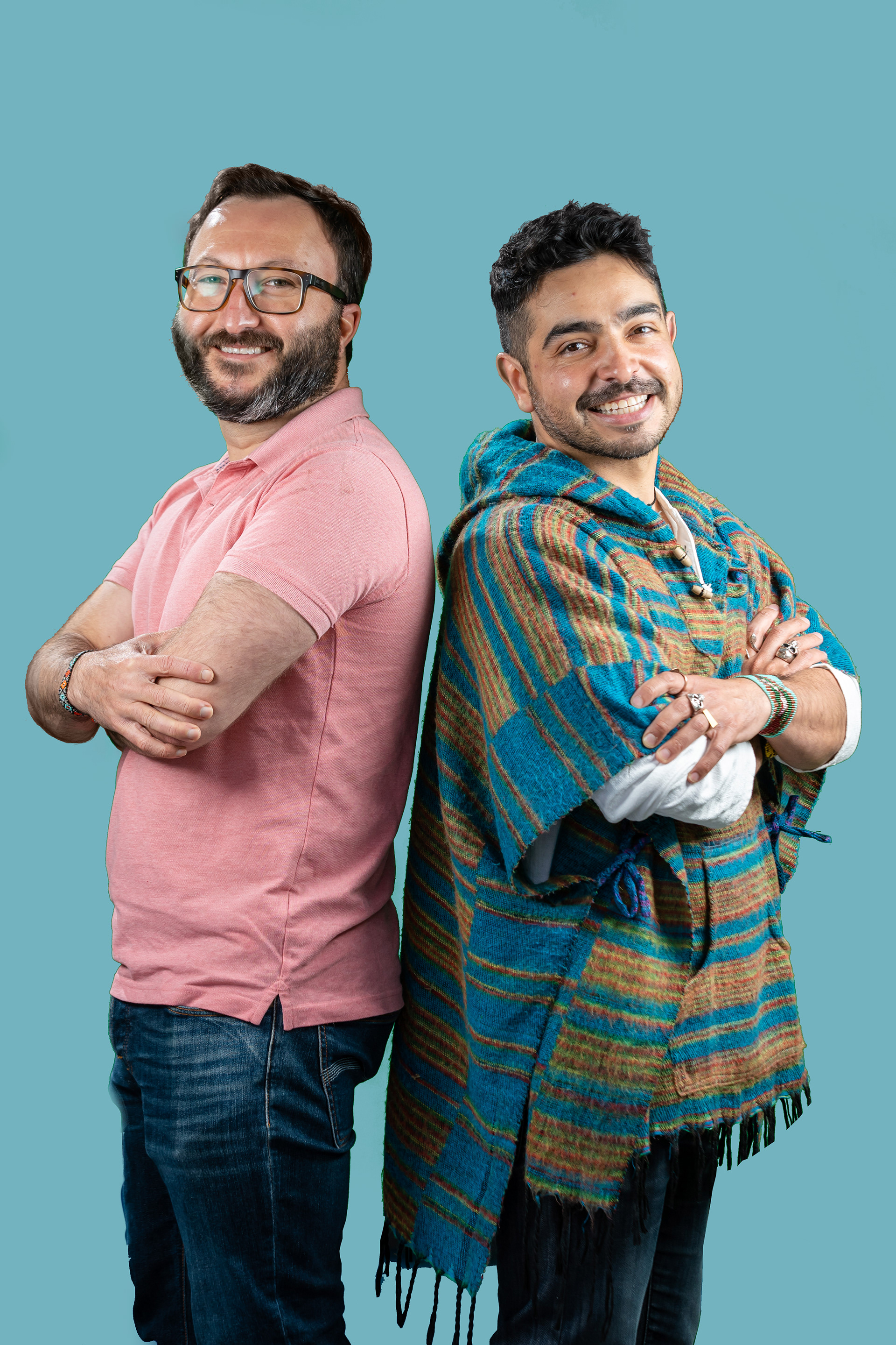 Two people posing together against a turquoise background