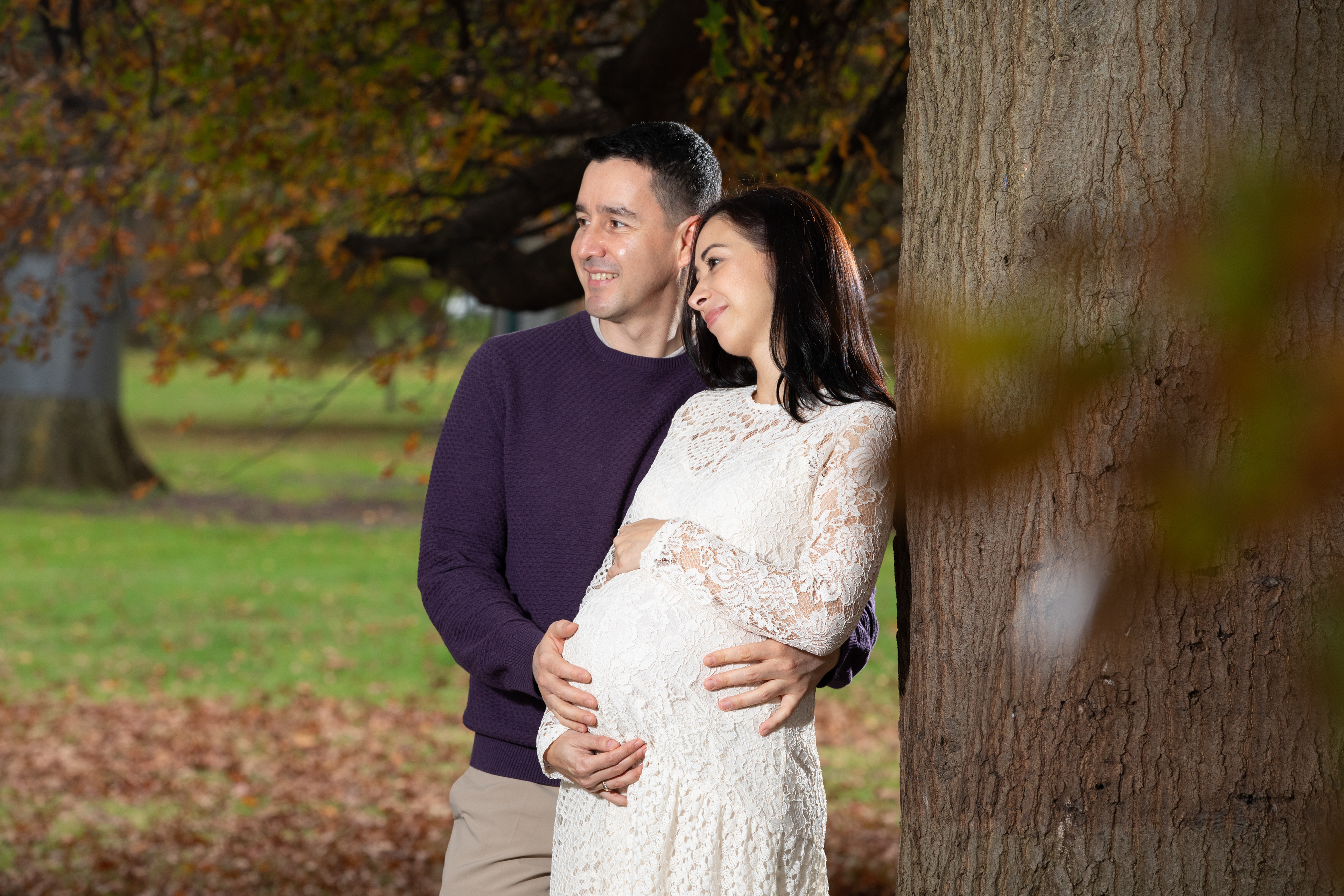 Couple standing together beneath autumn foliage