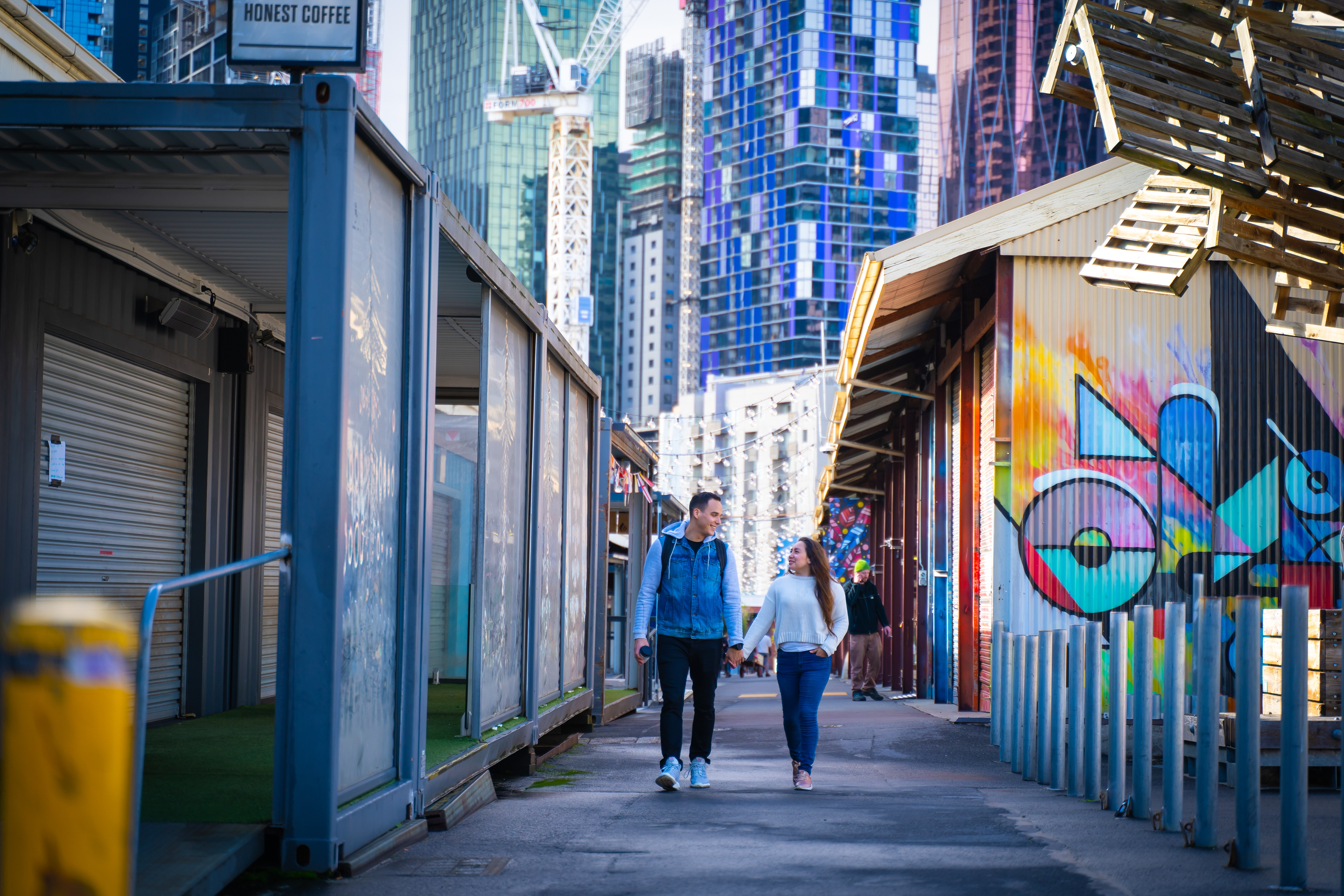 Wide view of a couple in a graffiti-lined city laneway