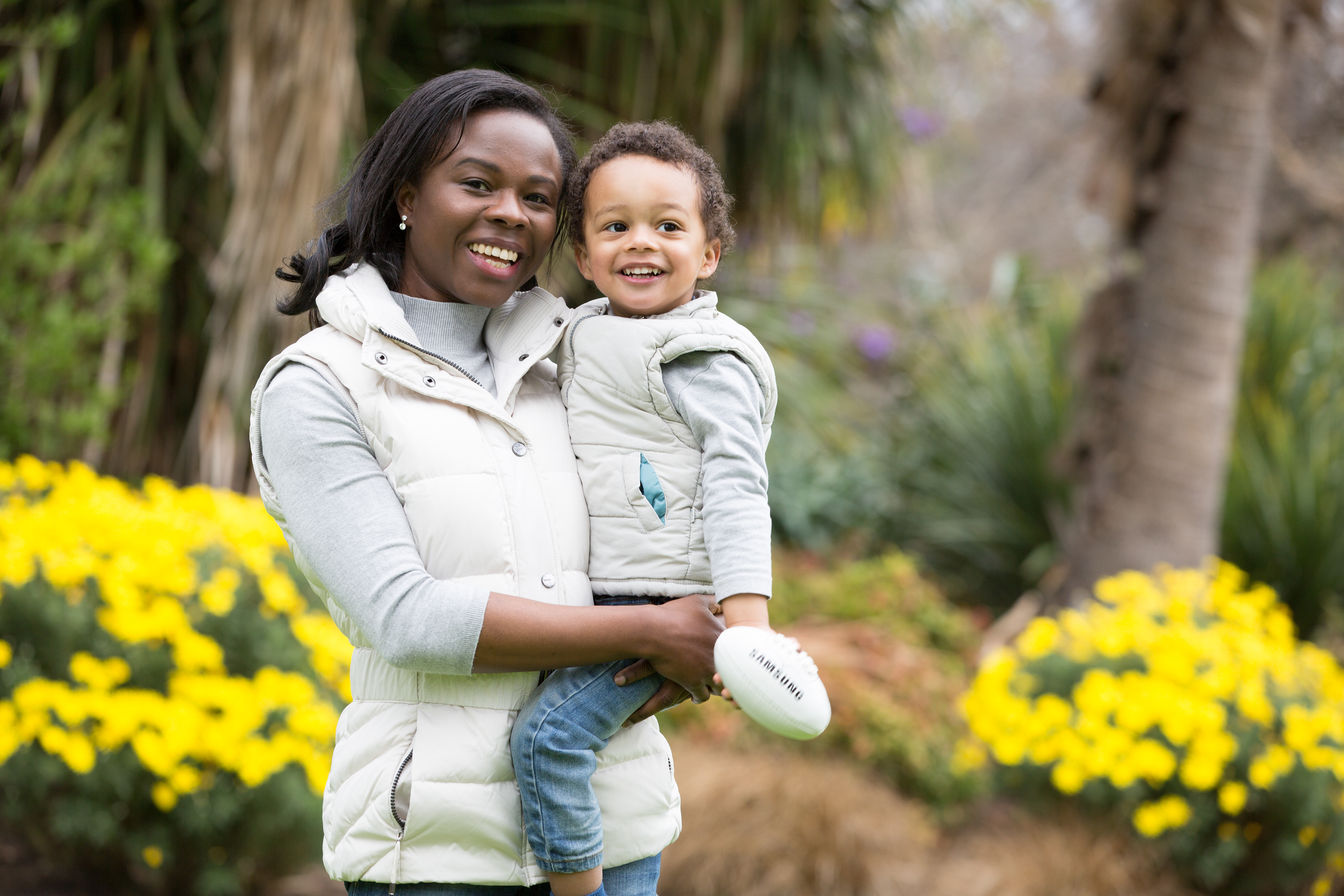 Parent holding a smiling child among yellow flowers