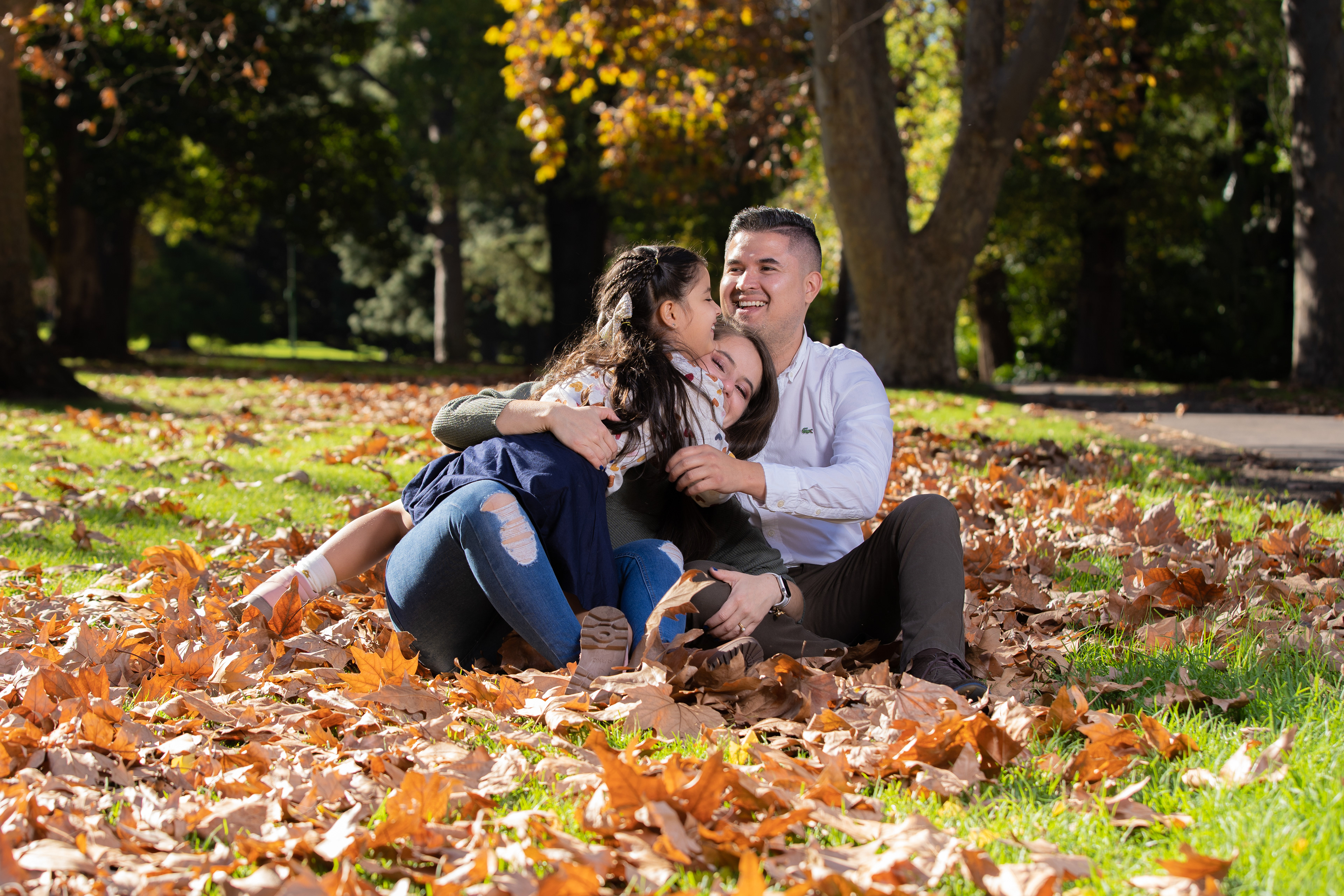 Family seated on a blanket among autumn leaves