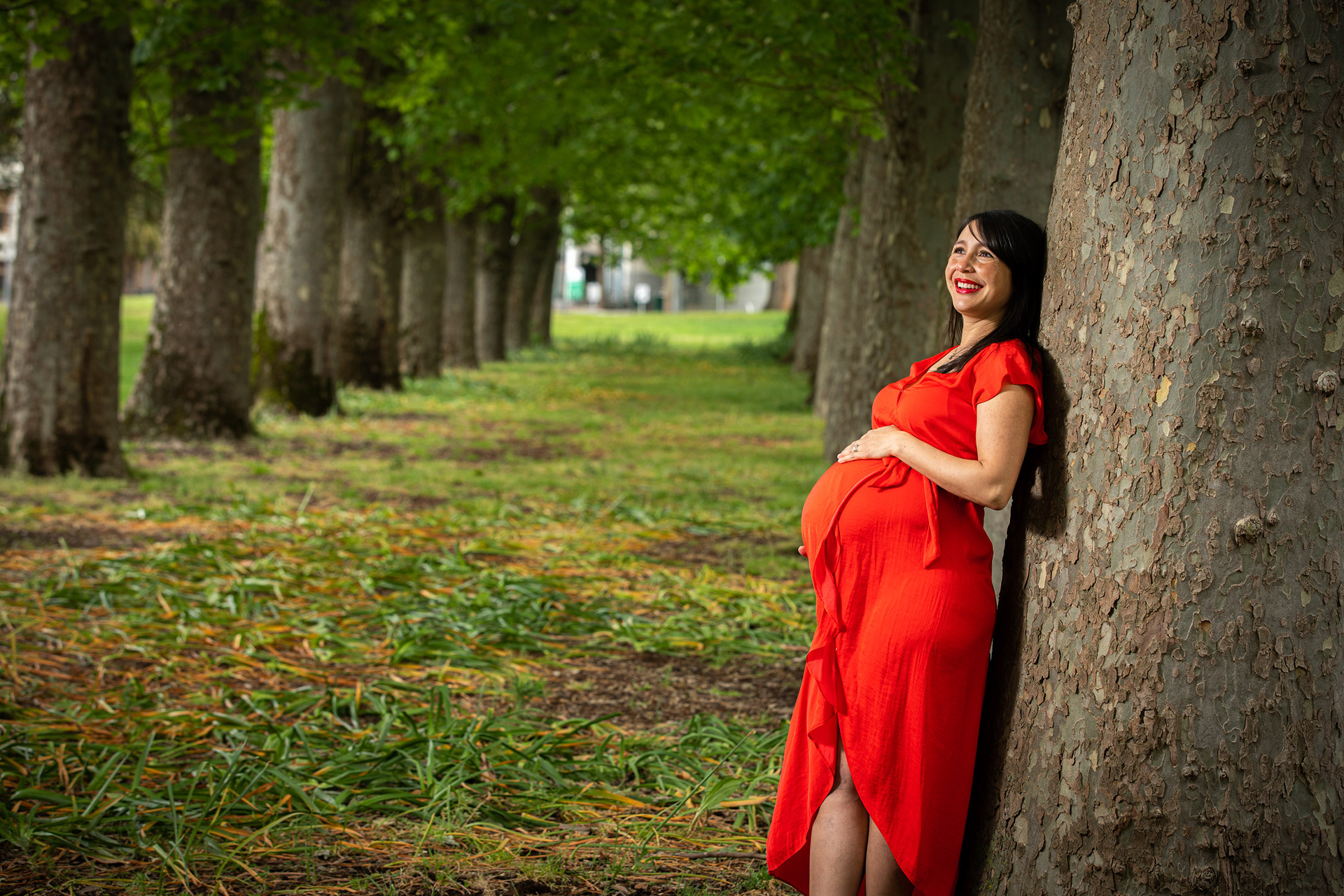 Maternity portrait in a red dress among trees
