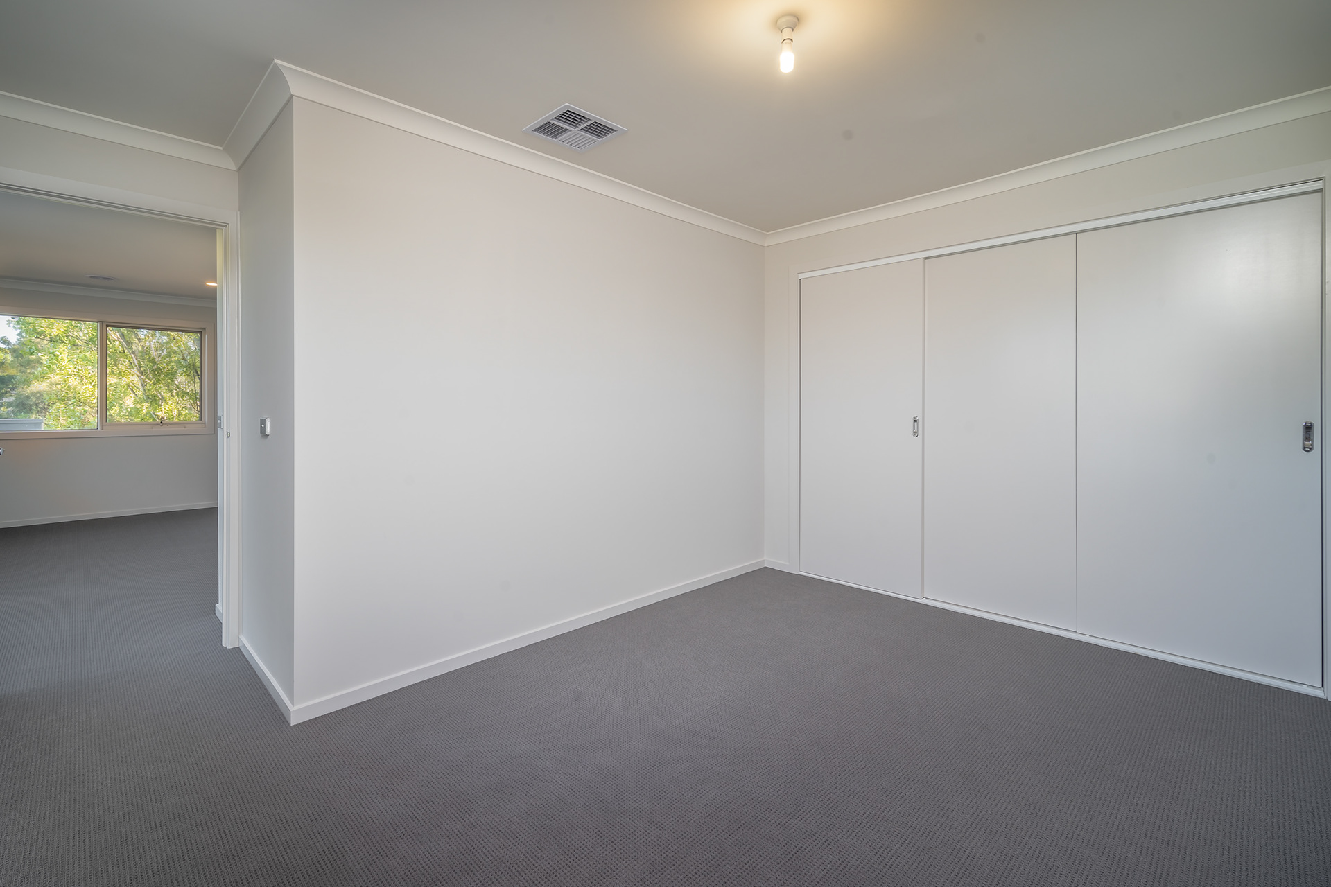 Empty carpeted bedroom with built-in wardrobes