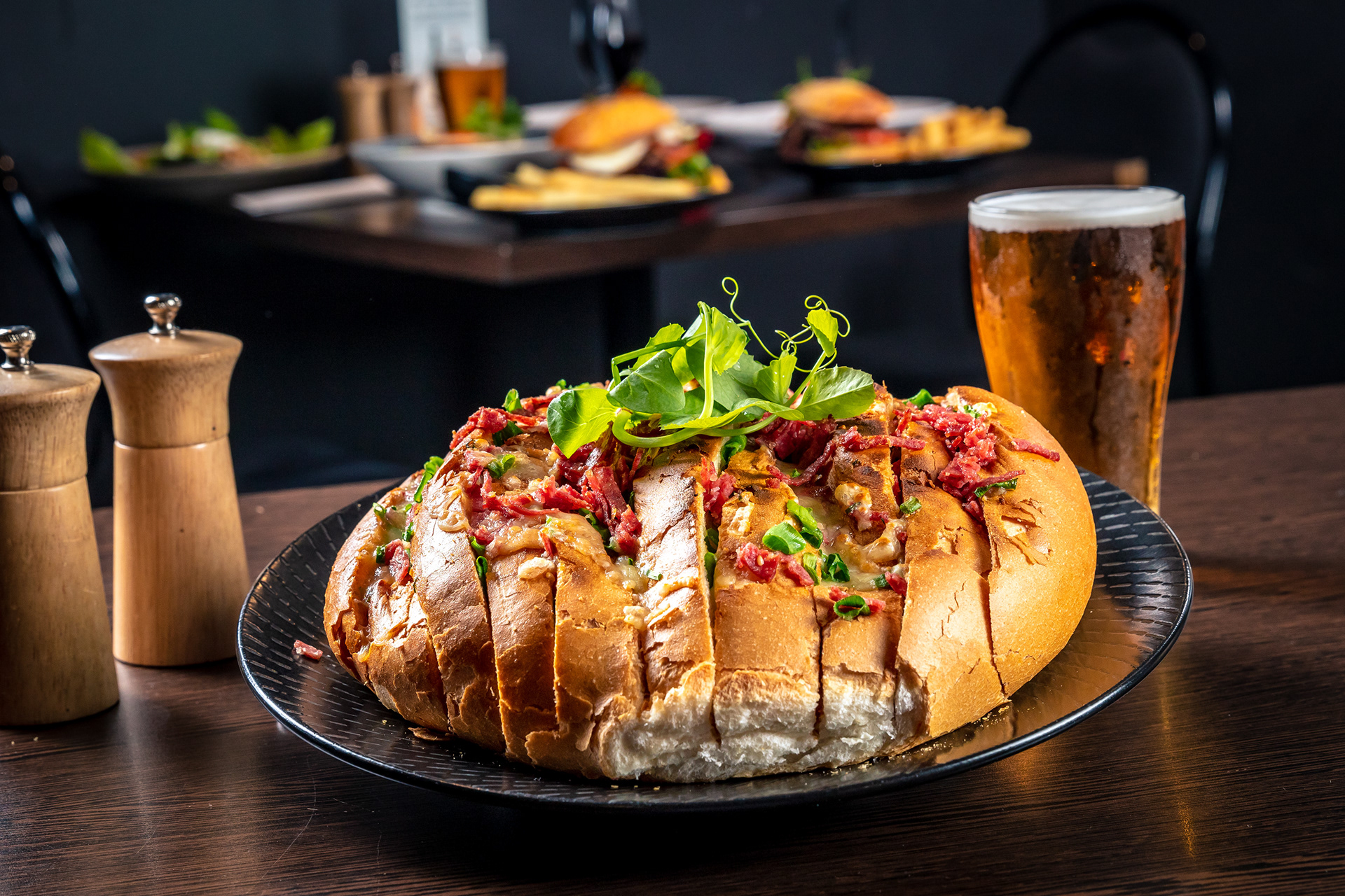 Burger presented beneath a lifted glass smoke dome
