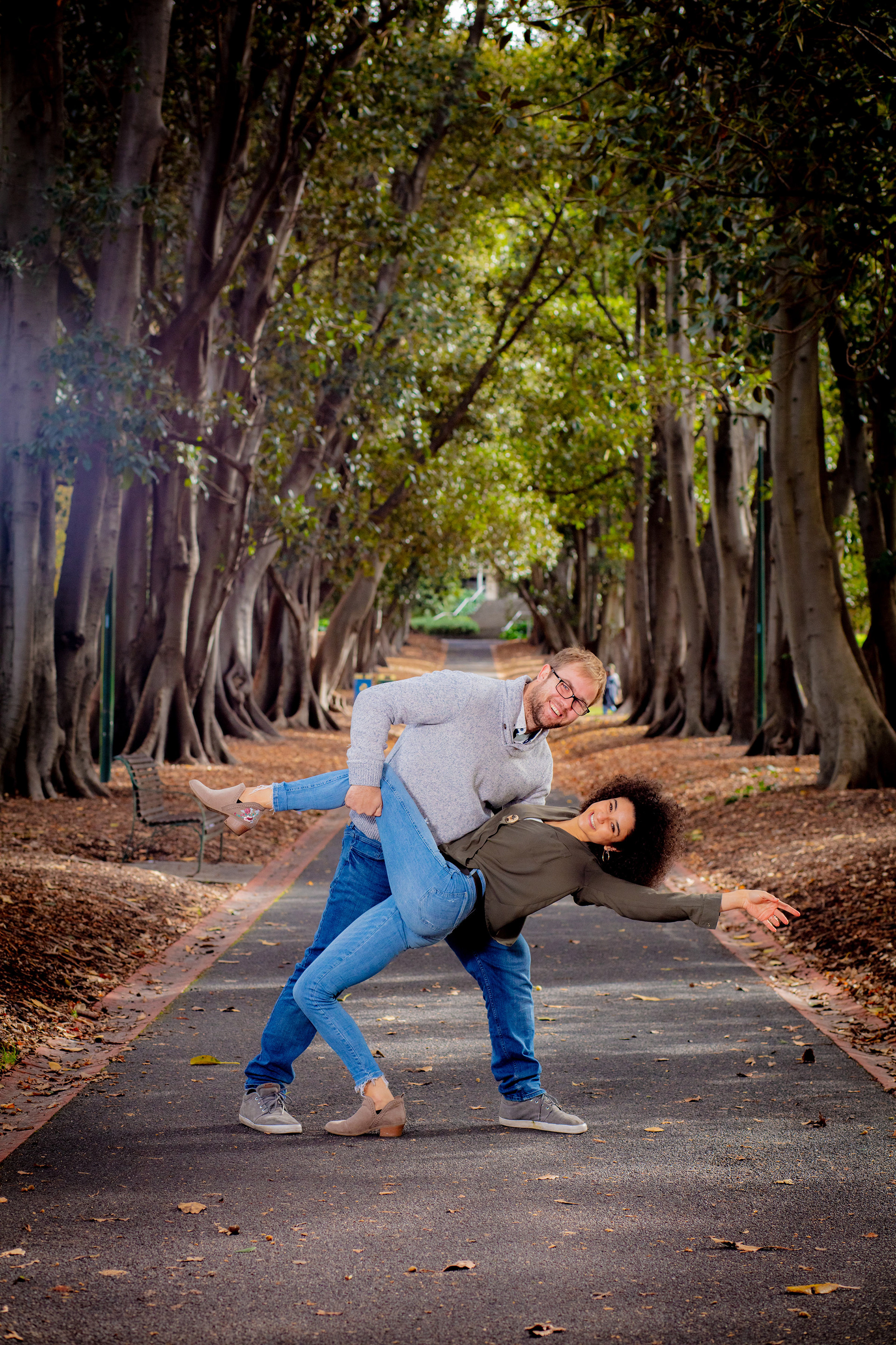 Couple sharing a playful pose along a wooded path