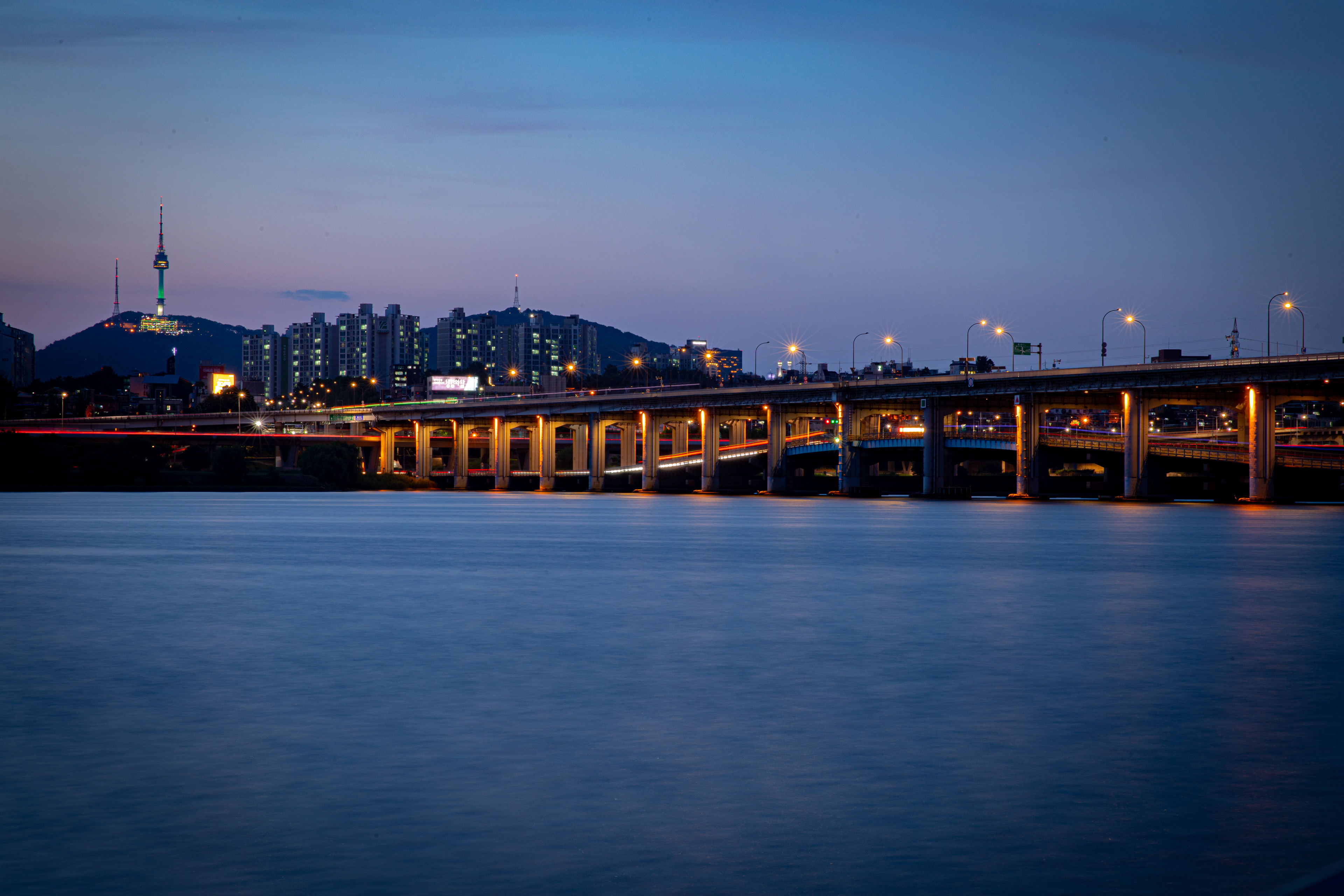 City bridge and lights reflected in a river at dusk