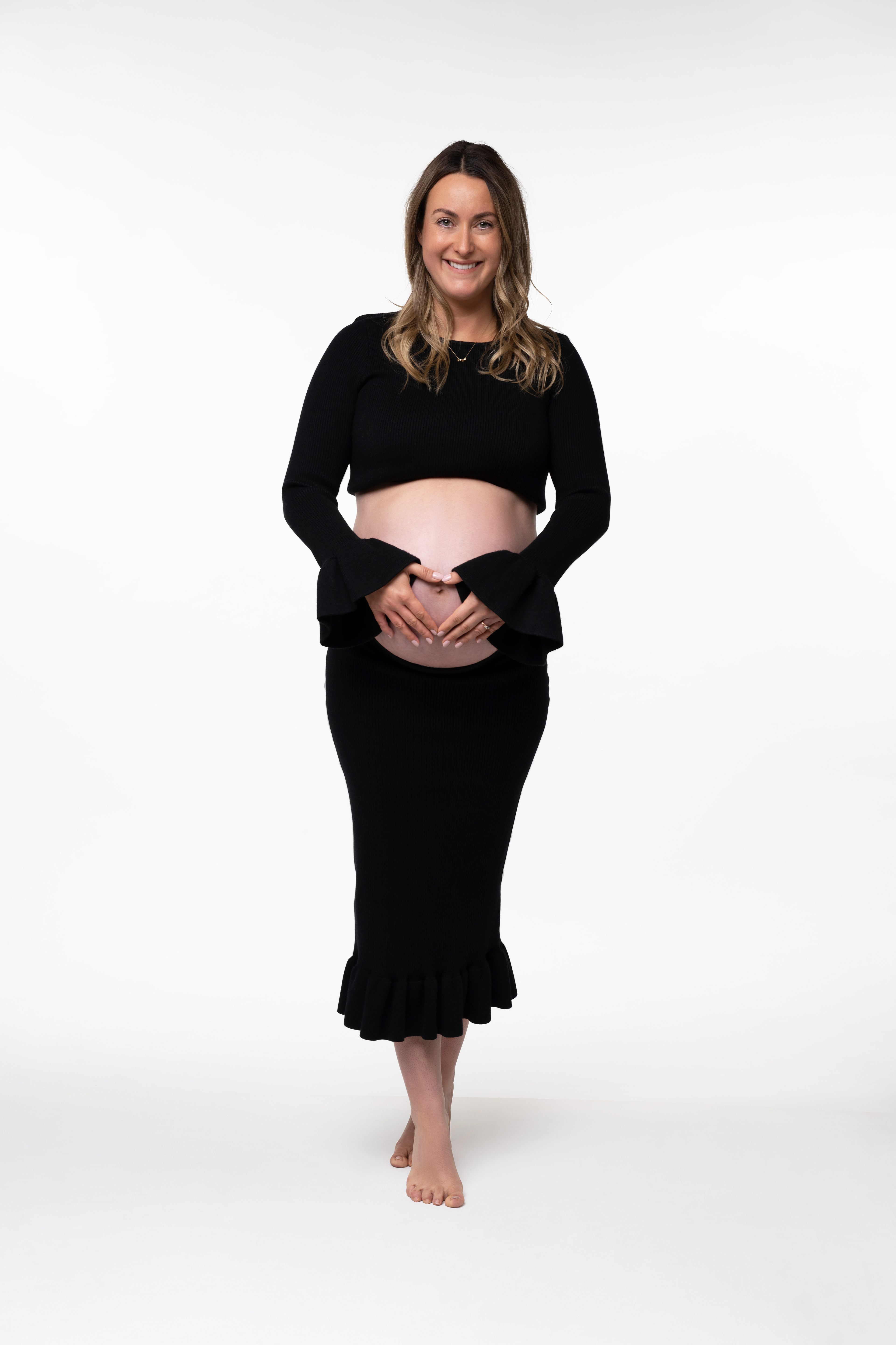 Full-length portrait in a black dress against white