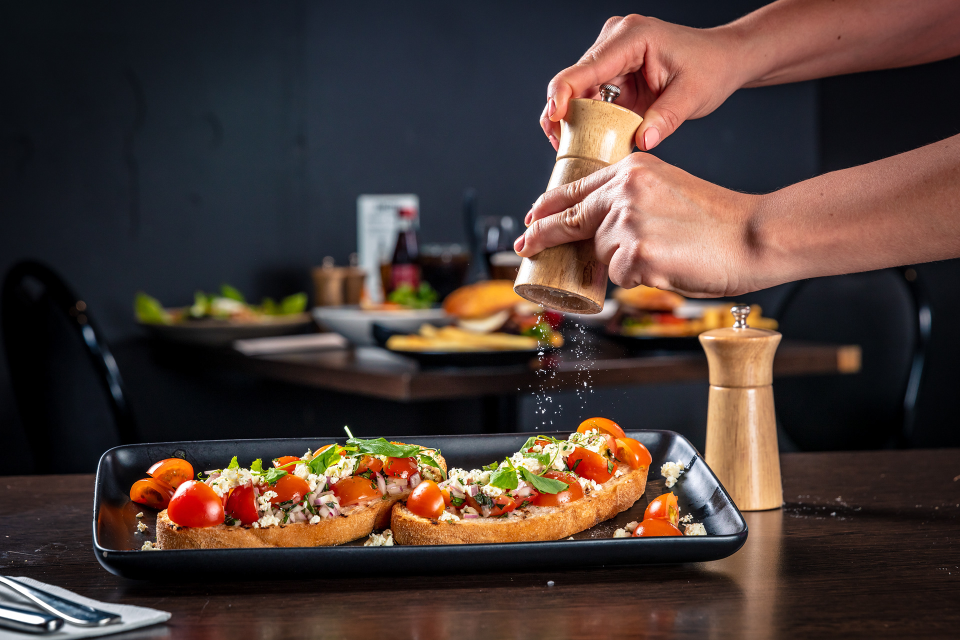 Chef adding finishing touches to food on a long serving plate