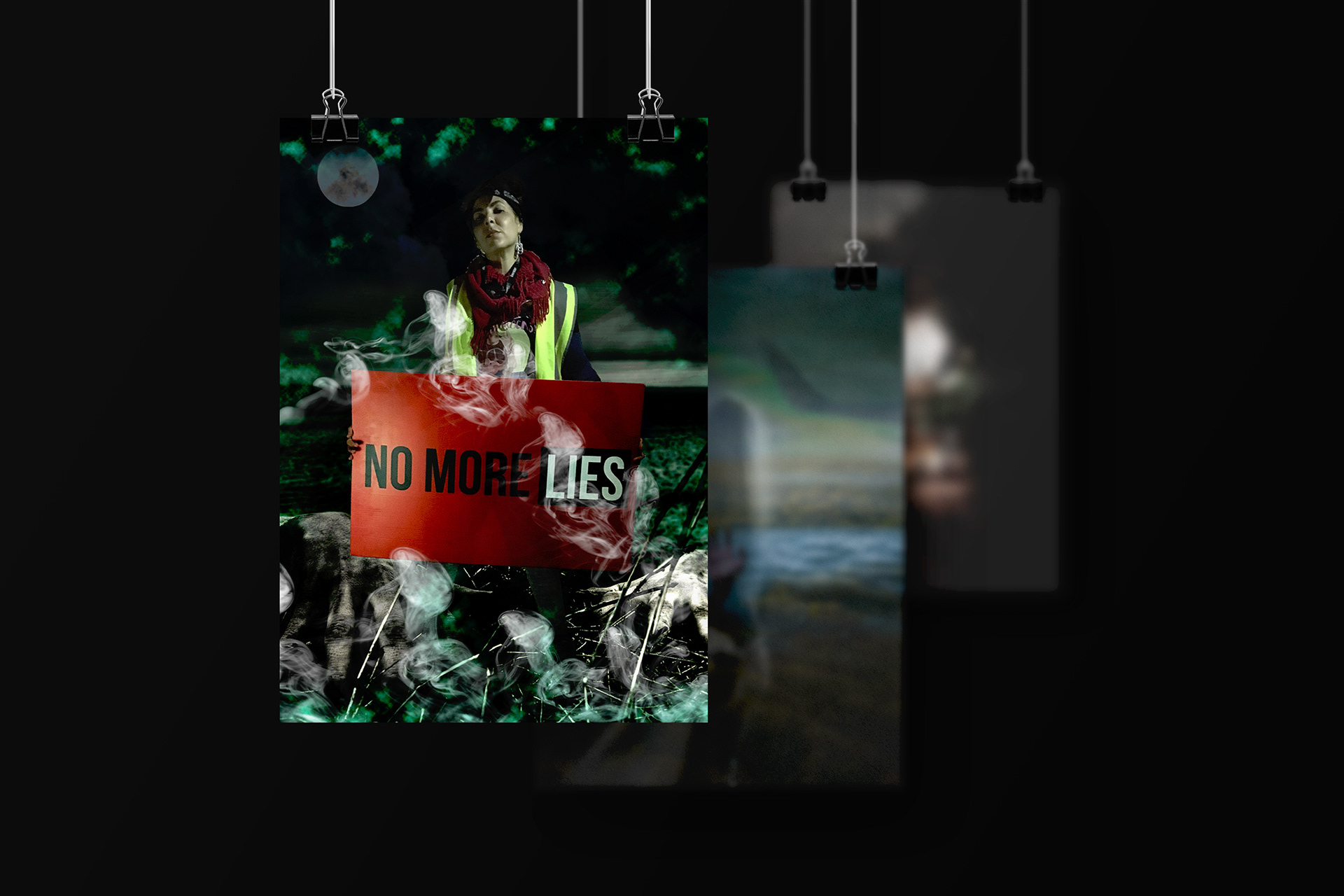 Three hanging poster mockups with the front poster as the main focal point. A woman stands on the edge of a cliff face while hands reach over the edge from below. Behind her is a dark ocean and a stormy, cloudy night with a full moon. Smoke rises from the ground and she holds a red corflute sign that says 'No more lies' in large black capital letters with the word Lies in white with a black square for emphasis.