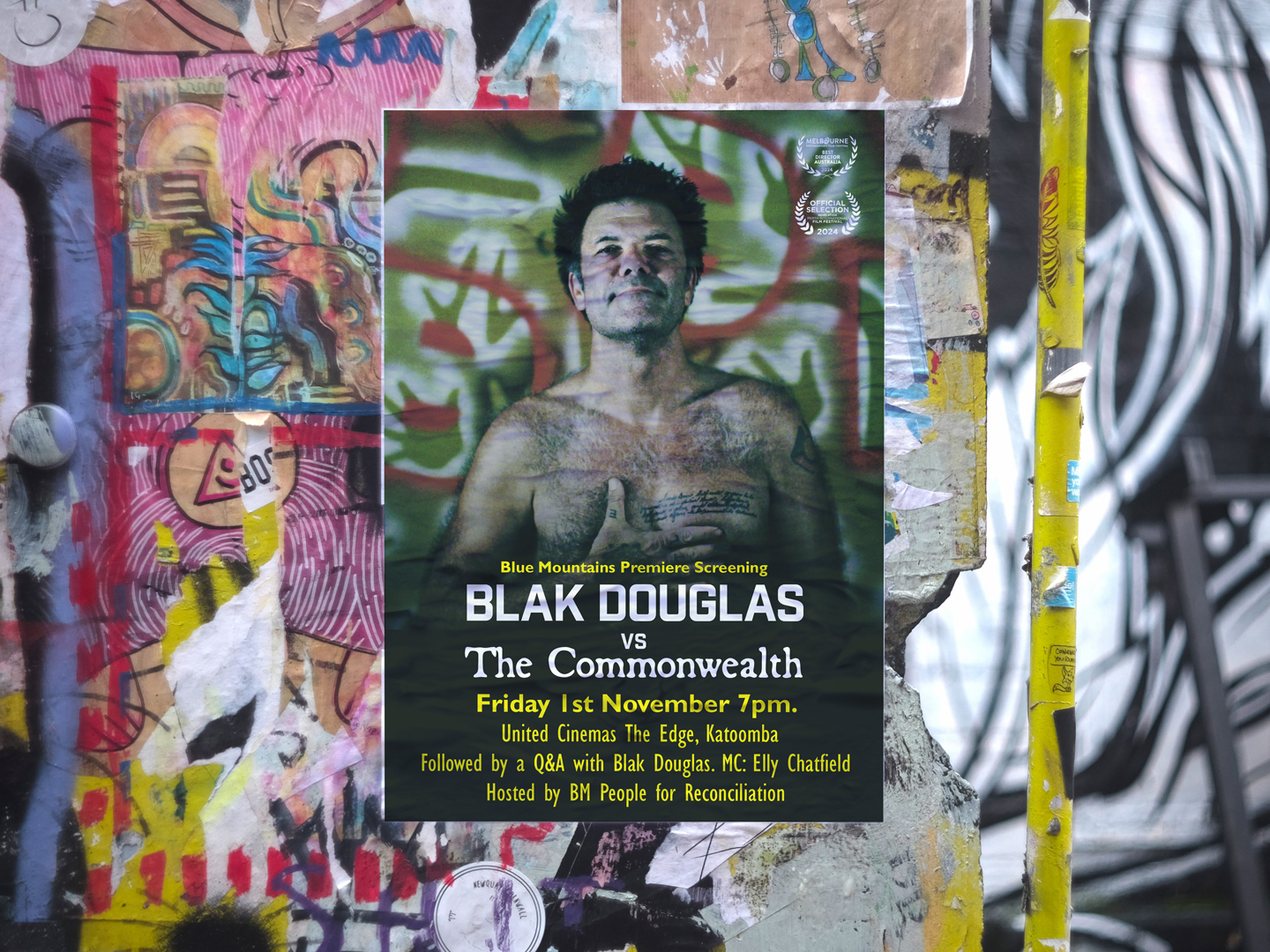 A movie poster mockup pasted onto a brightly colored graffiti wall in an urban street setting for the film 'Blak Douglas Vs The Commonwealth'. The poster features Blak Douglas staring directly at the camera with his right hand placed on his chest, standing against a green wall painted with motifs. In the foreground is the movie title, credits and sponsors in white type over a dark gradient overlay. There are also 4 laurels from documentary festivals and appearances