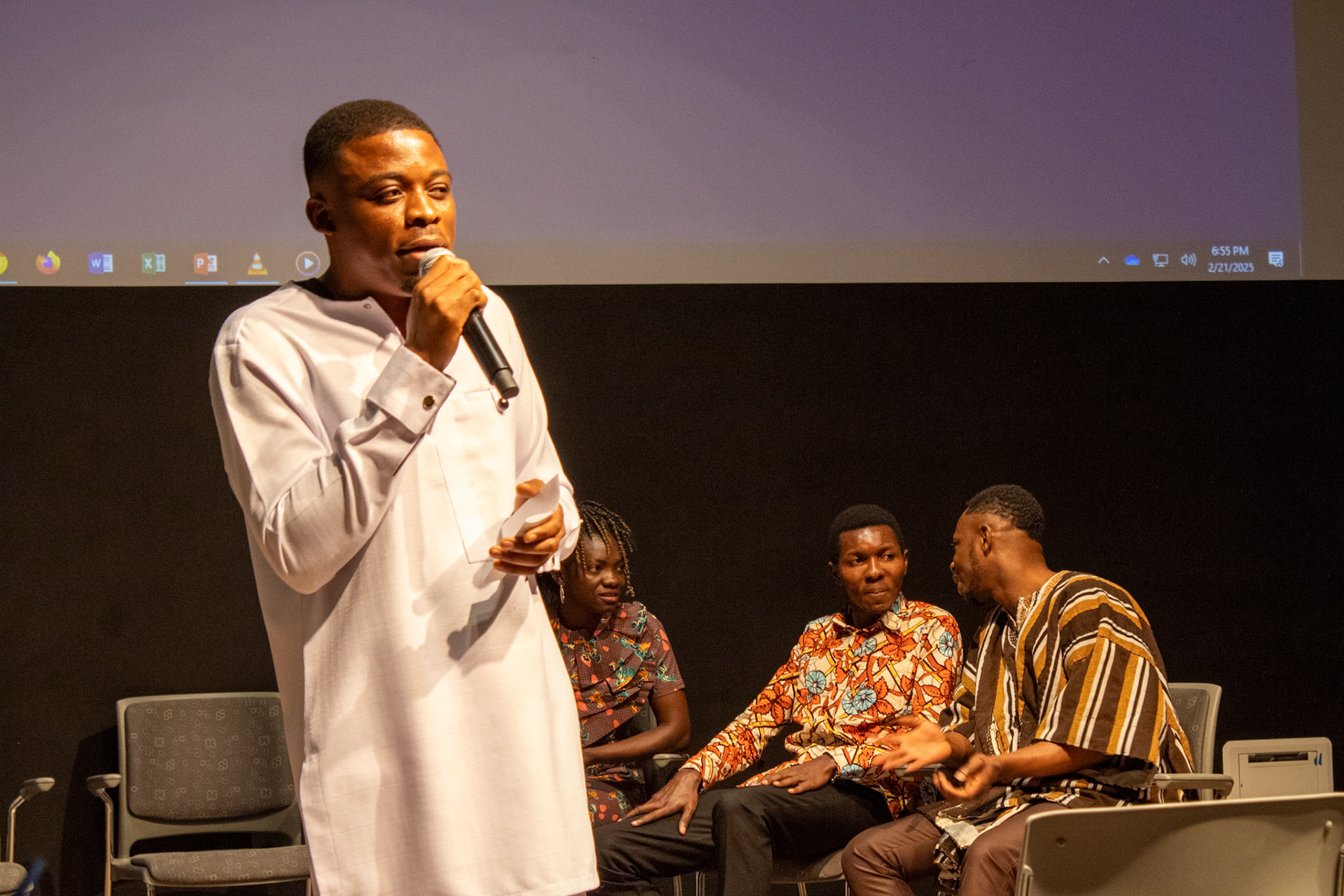 Man speaking to an audience at the NAU International Pavilion. 