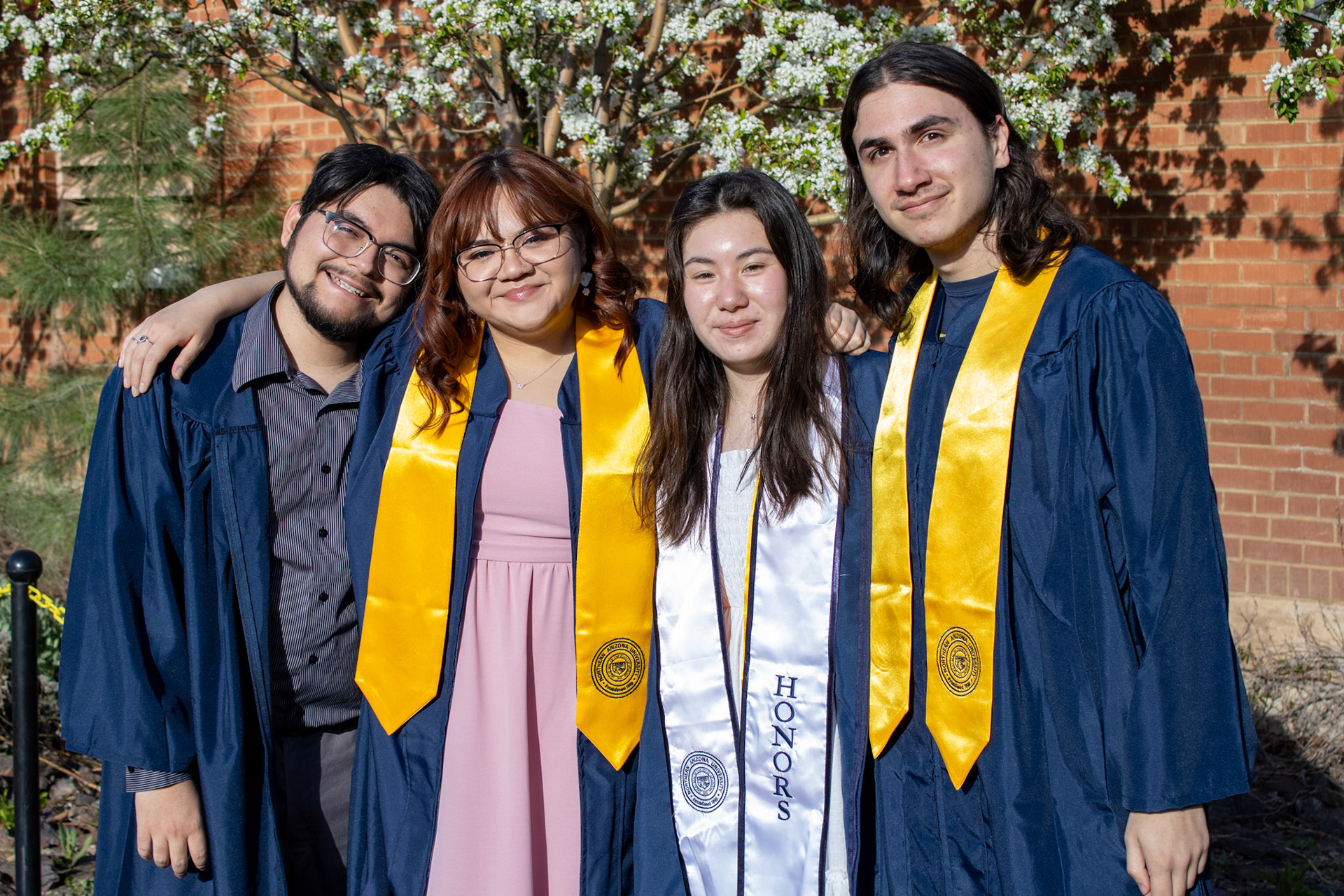 Graduate students smiling in front of trees. 