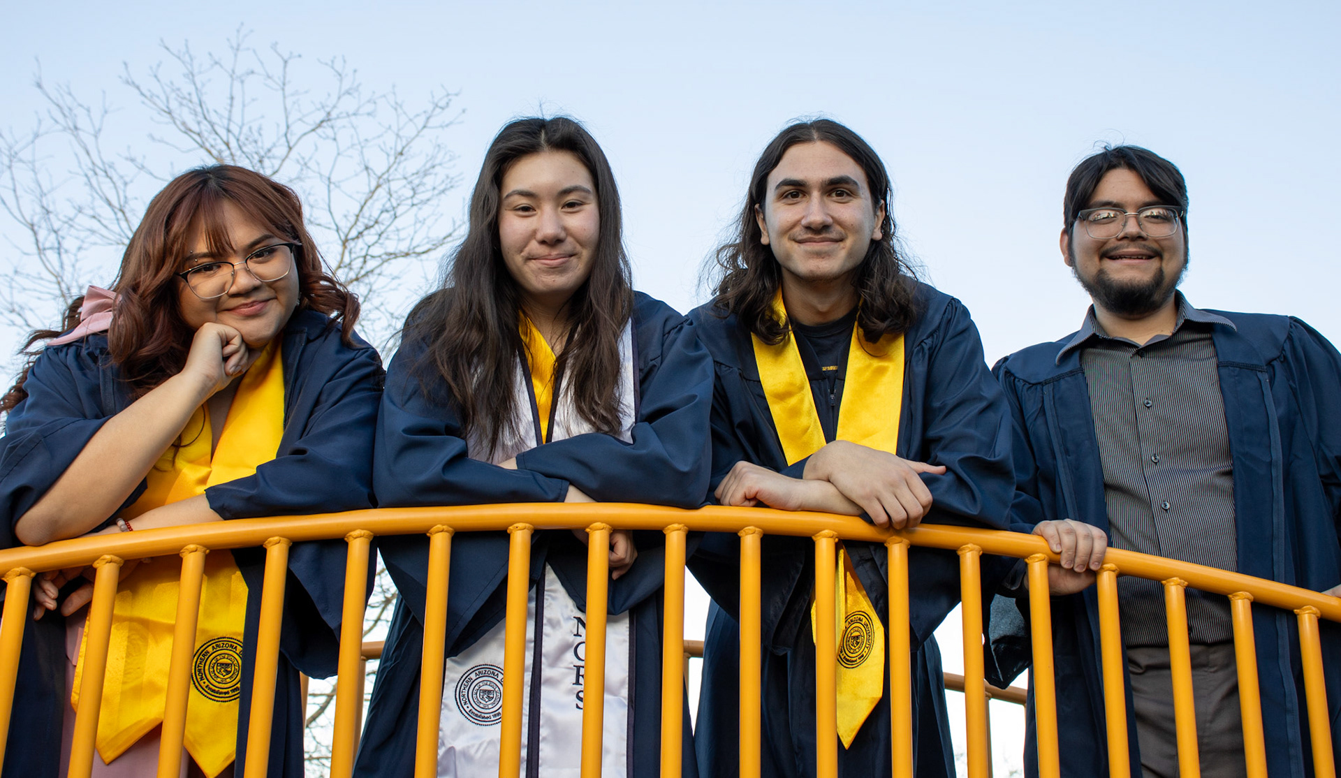 Graduate students smiling and posing on a bridge. 