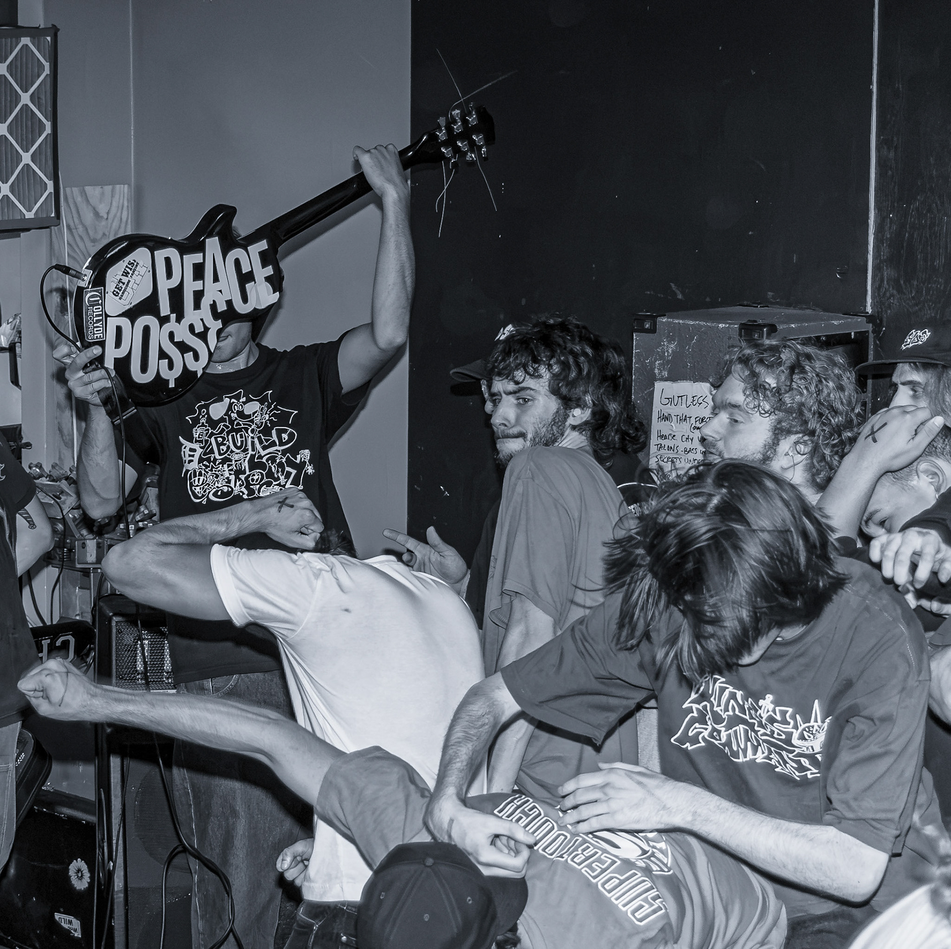 The Sissy Boys guitarist holds up his guitar featuring a custom “Peace Posse” design during a show at Refuge Skate Shop in Dearborn, Michigan. The message of peace on the guitar contrasts with the chaos surrounding him as fans collide and mosh in the crowd. Photo by Brayden Gallagher