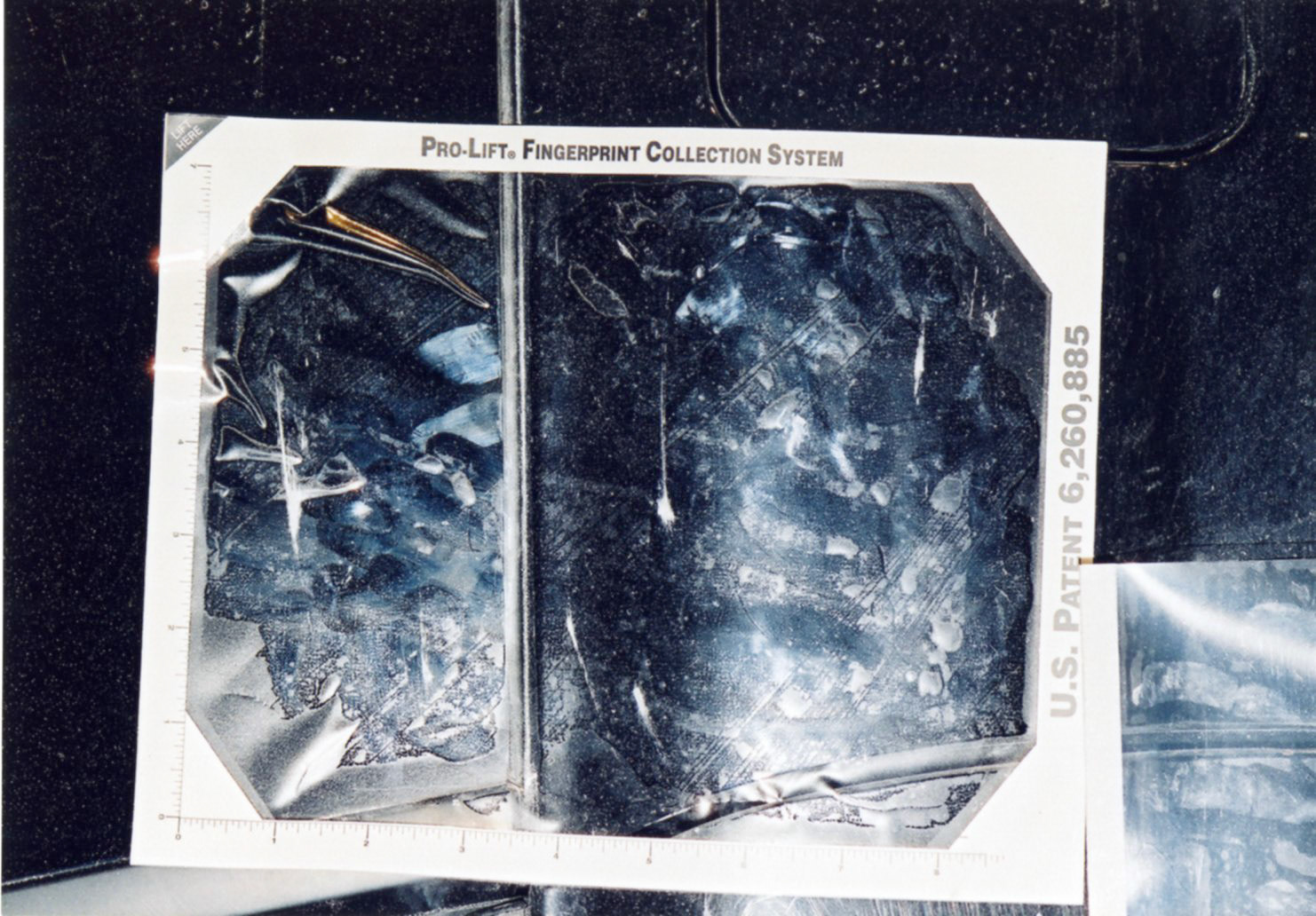 Evidence team lifting fingerprints from car exterior.