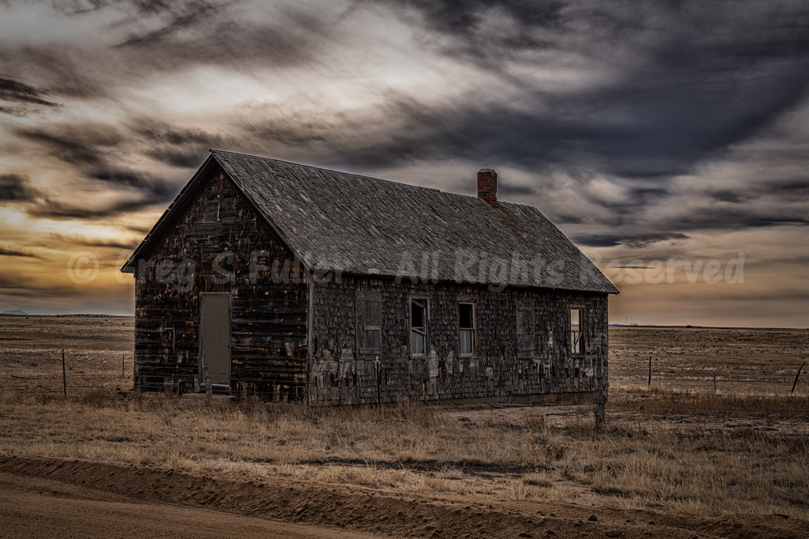 Under a ominous sunset skies, a lonely old schoolhouse on the plains in a ghost of a town - Cowans, Colorado