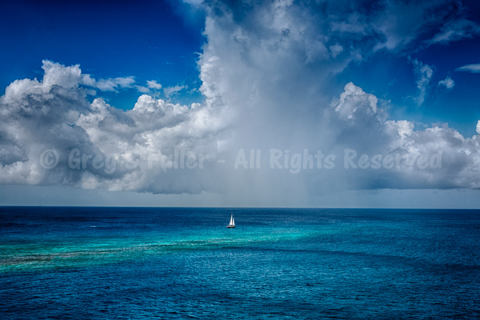A Small Boat in a Big Sea Sailing into Turquoise Waters with Large Billowy White Clouds - Curacao