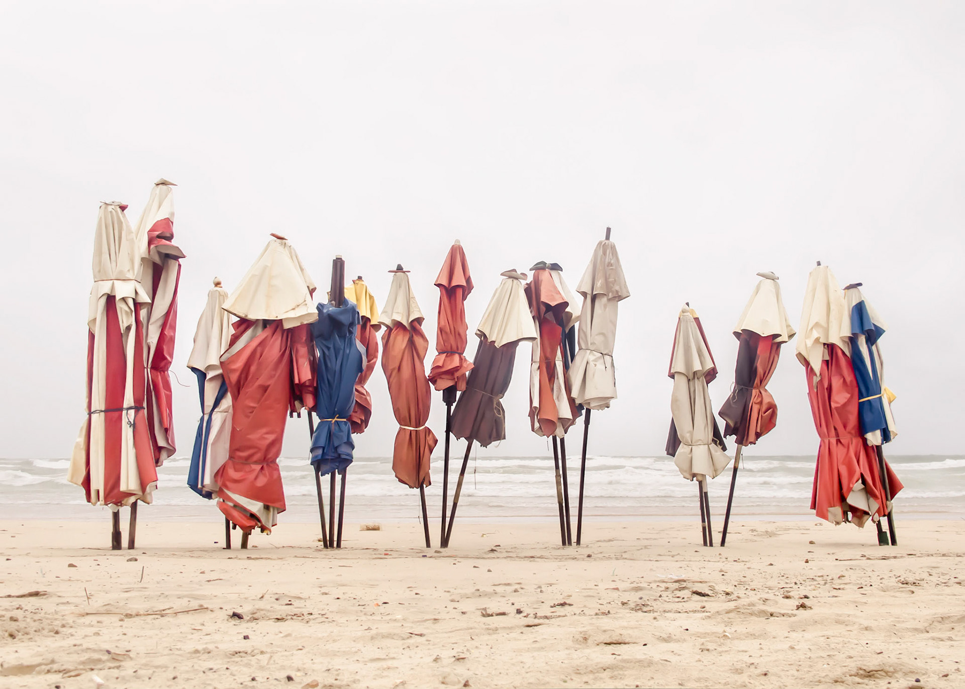 Caboclo Cafuzo Mulato - Arbitrary terms designating mixed races (Europeans and Indians, Indians and Africans, Africans and Europeans, respectively) that were used to consolidate racism as a form of social oppression. Yet, red is the color of our blood.Caboclo - One of Umbanda’s entities: a well-intentioned ancient indian spirit.Mulato - From the Portuguese word mula (mule), the hybrid offspring of a horse and a donkey.Urucum - Tupi word meaning red. Seed of an homonymous tree rubbed by Indians on their bodies to provide protection against sun rays and insect bites. Forgotten color of the national flag. As red as bloodPart of Liquid Beach series:As hut owners begun to be expelled from the sands of Salvador’s beaches, their resistance took shape through umbrellas and plastic tables, mythical symbols of the local culture. Their colorful shapes erected against the gloomy horizon set the stage for a visual dictionary of the country's social-economic history, each title referring to an issue yet to be resolved.Liquid - Drinkable amorphous substance. When ingested in despair causes drowning (or drunkenness). Humanity’s current state according to Bauman. Quality of the blood that flows.Beach - Brazilian history’s primordial stage. Where work, leisure and belief mingle. Where blood is boiled, poured and mixed. From where one can see the horizon and feel “saudade”. Where umbrellas arise as sculptures above the sand, watching over the people as saints and orixás.