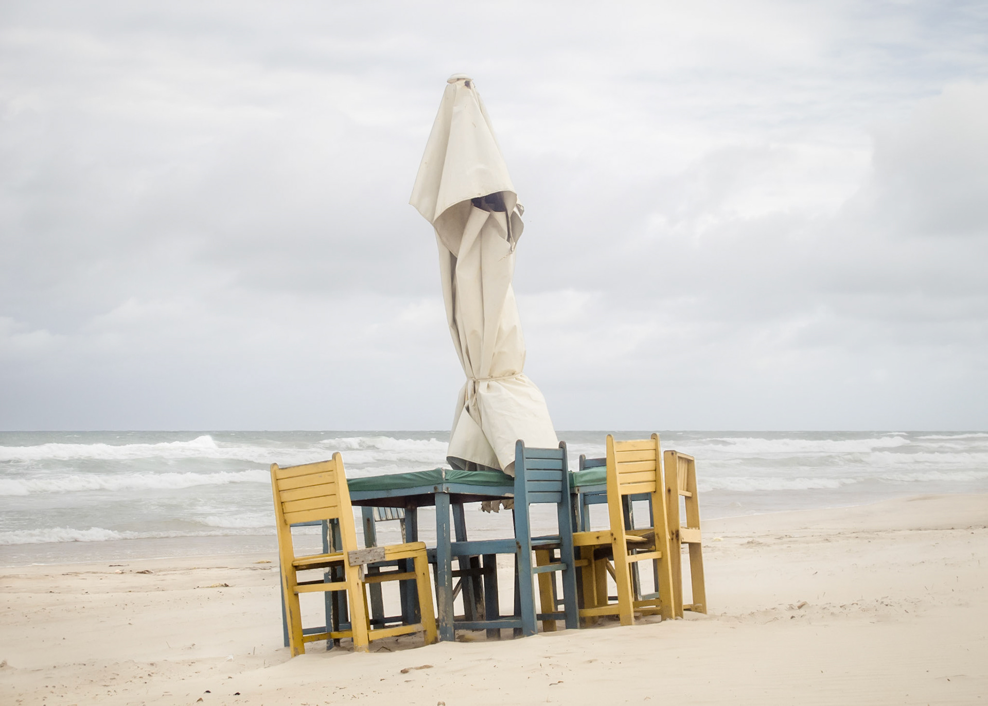 Gentile Feast - 	Prophetic event of the nation in which Caetés Indians devoured Bishop Pero Fernandes Sardinha after his shipwreck on the Brazilian coast, as remembered by Oswald de Andrade in his Anthropophagic Manifest.Part of Liquid Beach series:As hut owners begun to be expelled from the sands of Salvador’s beaches, their resistance took shape through umbrellas and plastic tables, mythical symbols of the local culture. Their colorful shapes erected against the gloomy horizon set the stage for a visual dictionary of the country's social-economic history, each title referring to an issue yet to be resolved.Liquid - Drinkable amorphous substance. When ingested in despair causes drowning (or drunkenness). Humanity’s current state according to Bauman. Quality of the blood that flows.Beach - Brazilian history’s primordial stage. Where work, leisure and belief mingle. Where blood is boiled, poured and mixed. From where one can see the horizon and feel “saudade”. Where umbrellas arise as sculptures above the sand, watching over the people as saints and orixás.