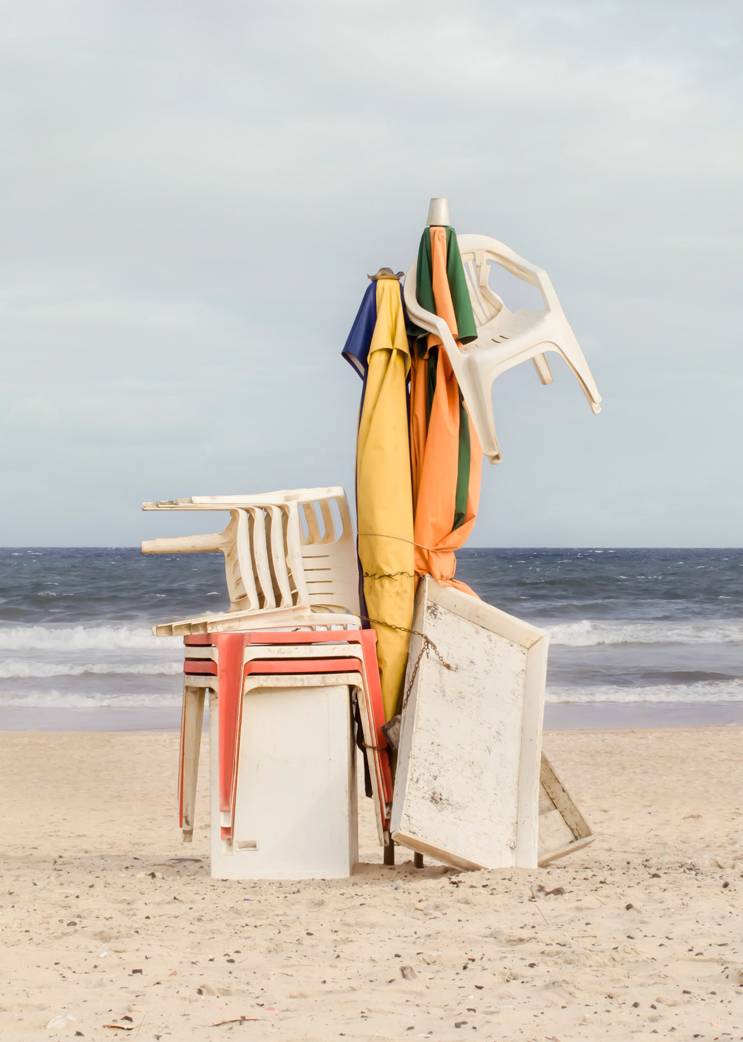 Castle - Playful form made of sand. A symbol of resistance. A fortress created by the fear of one’s own territory. Life contained by walls and metal fences.Part of Liquid Beach series:As hut owners begun to be expelled from the sands of Salvador’s beaches, their resistance took shape through umbrellas and plastic tables, mythical symbols of the local culture. Their colorful shapes erected against the gloomy horizon set the stage for a visual dictionary of the country's social-economic history, each title referring to an issue yet to be resolved.Liquid - Drinkable amorphous substance. When ingested in despair causes drowning (or drunkenness). Humanity’s current state according to Bauman. Quality of the blood that flows.Beach - Brazilian history’s primordial stage. Where work, leisure and belief mingle. Where blood is boiled, poured and mixed. From where one can see the horizon and feel “saudade”. Where umbrellas arise as sculptures above the sand, watching over the people as saints and orixás.