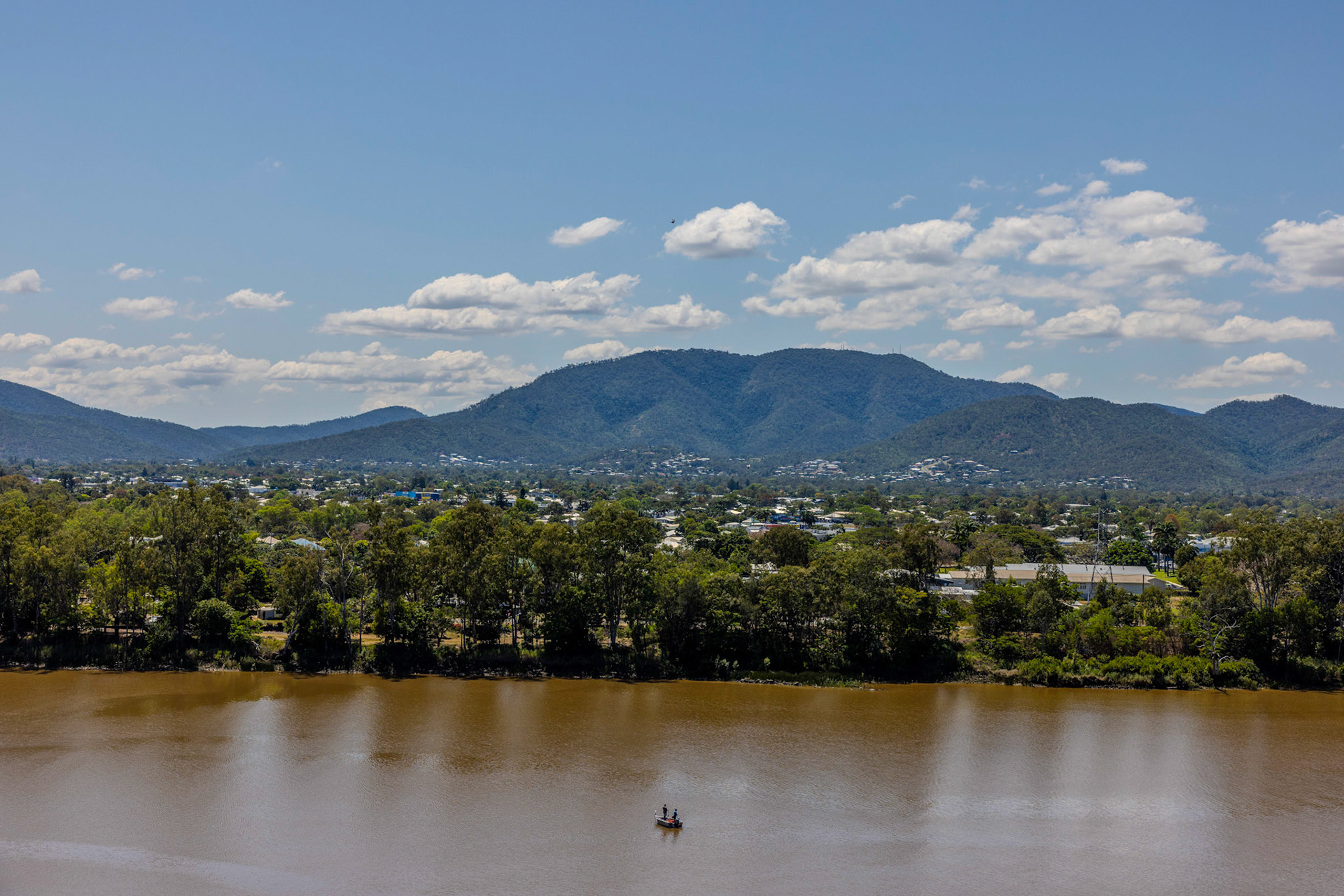 Fitzroy River Rockhampton, Central Queensland. A peaceful scene unfolds in Rockhampton, with a small fishing boat drifting along the Fitzroy River and the vast landscape stretching into the distance. Capturing the natural beauty and quiet resilience of the region, the river plays a vital role in connecting the community to its surrounding environment.