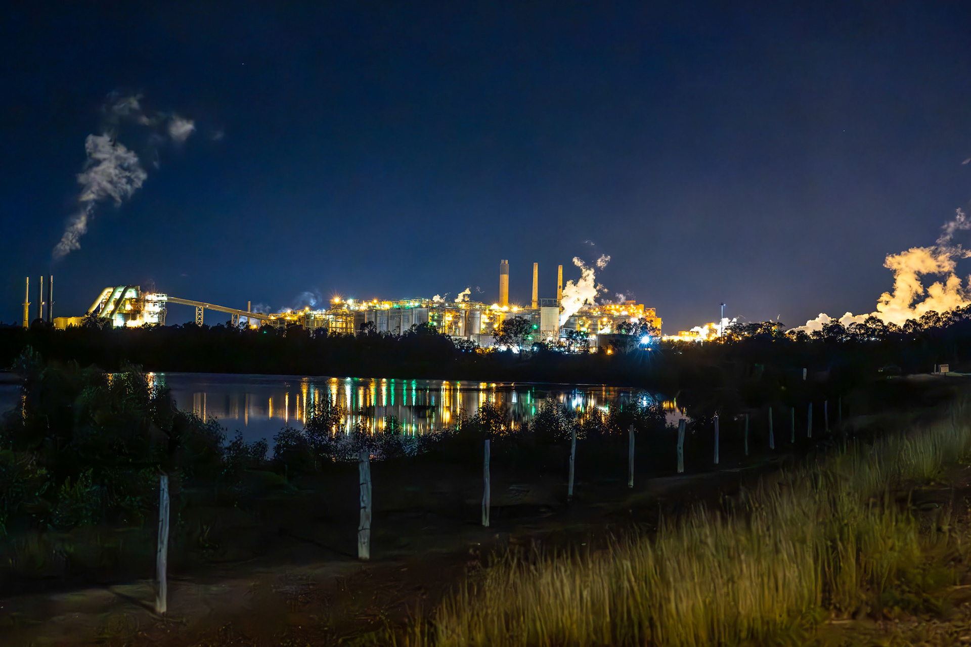 Night lights on Queensland Alumina Ltd smelter Gladstone. The illuminated Queensland Alumina Ltd smelter stands out against the night sky in Gladstone, a symbol of the region’s pivotal role in the alumina and aluminium industries. This facility operates around the clock, contributing to the local economy and symbolising the region’s industrial heritage.