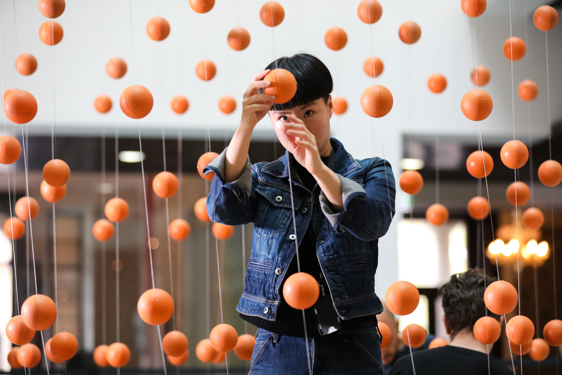 Customs House Sydney - 4th October 2018.  Portrait of artist Danling Xiao installing Wasteland. Art and About Sydney have commissioned Sydney-based creative studio Mundane Matters to produce the thought-provoking artwork Wasteland. Made from 120kg of marine debris collected from the Great Barrier Reef, Wasteland voices 2 of the world’s most urgent problems: plastic pollution and food waste.Suspended from the ceiling of Customs House, the rescued materials have been reimagined as 2,255 objects that resemble oranges.