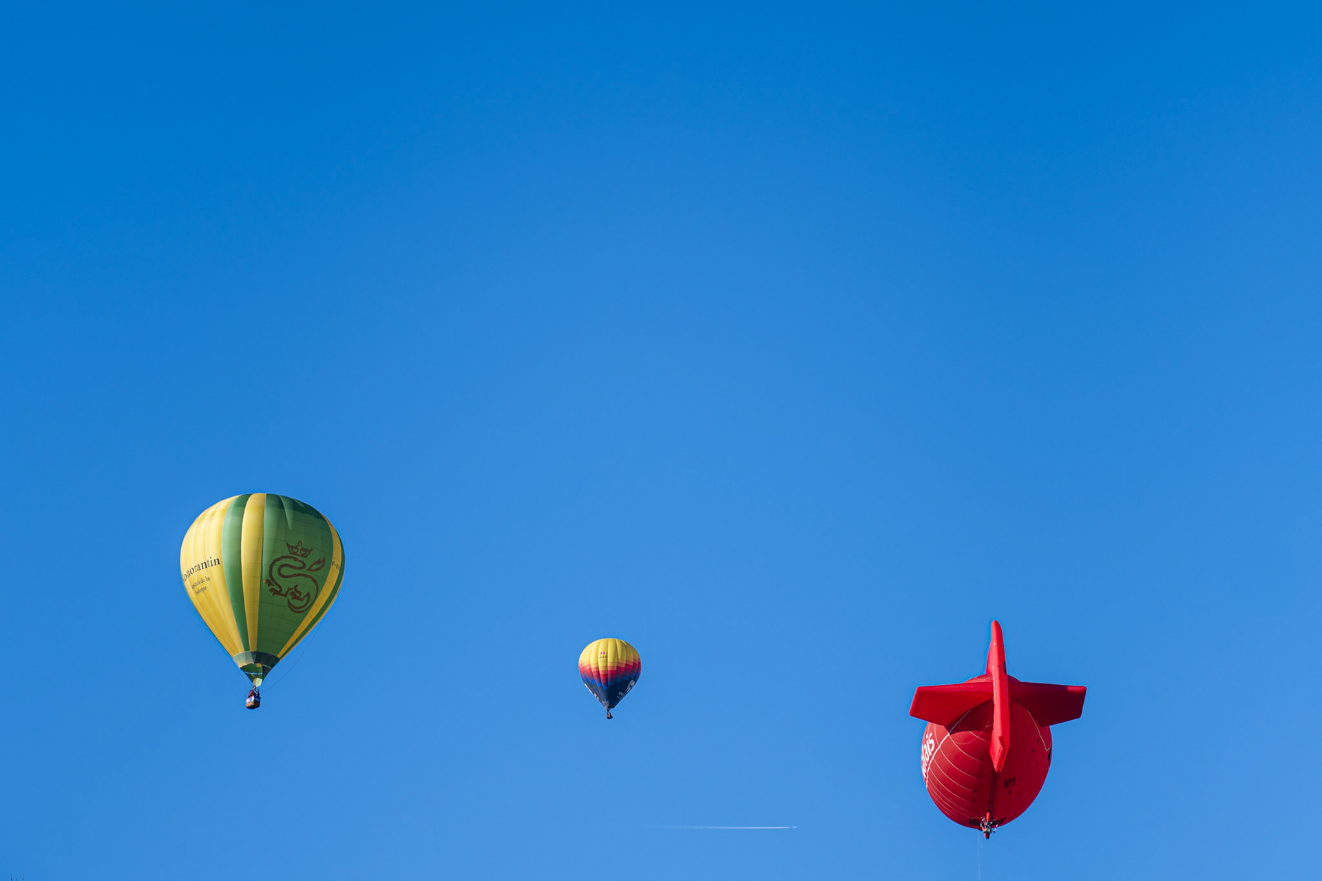 different shaped balloons in the blue sky during the 45th Festival International de Ballons