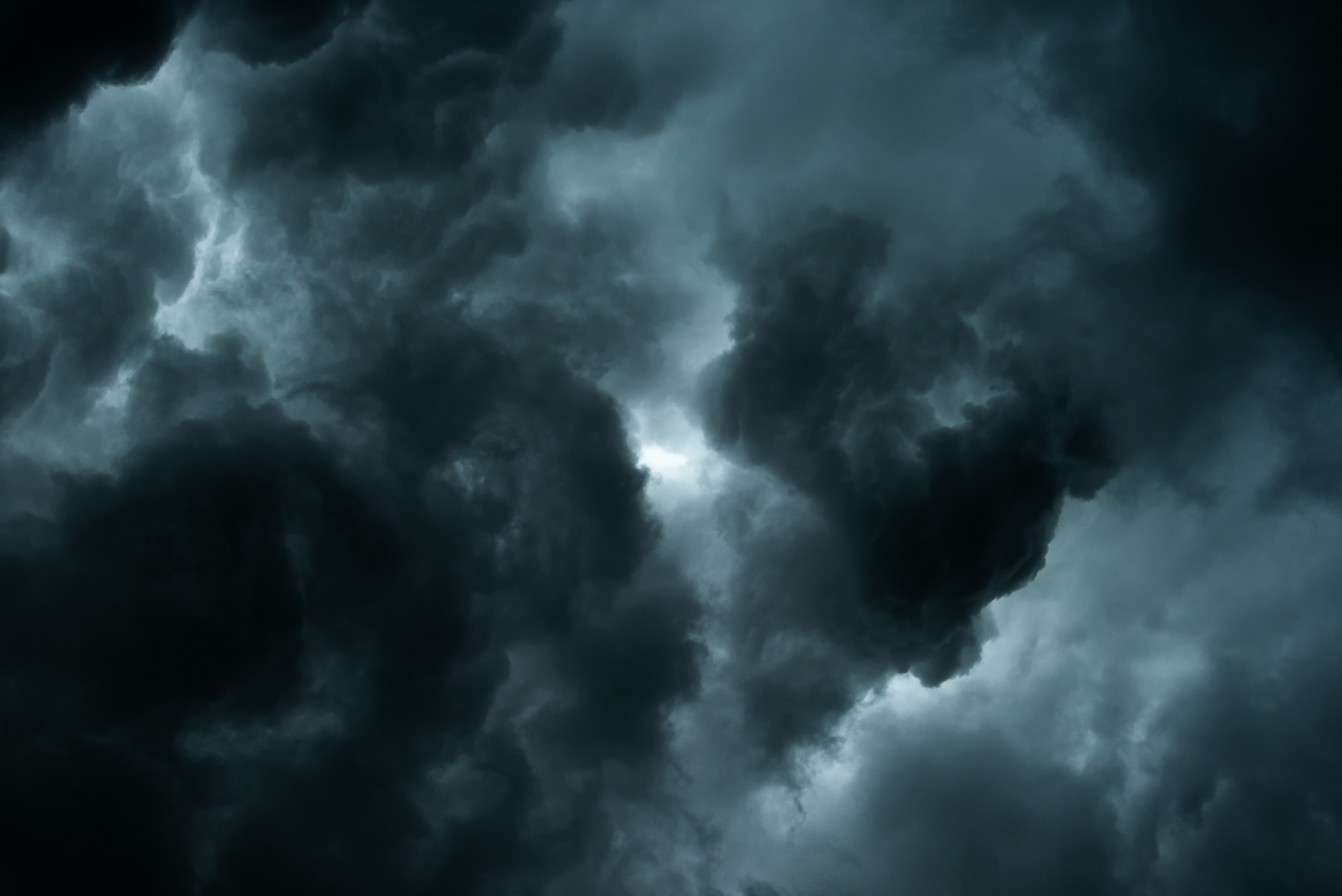 A black and white photo of storm clouds with a patch of light.