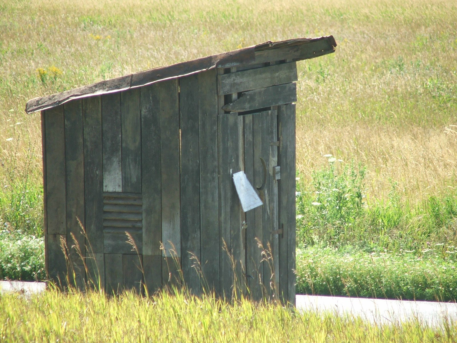 old-western-outhouse-alone-in-field