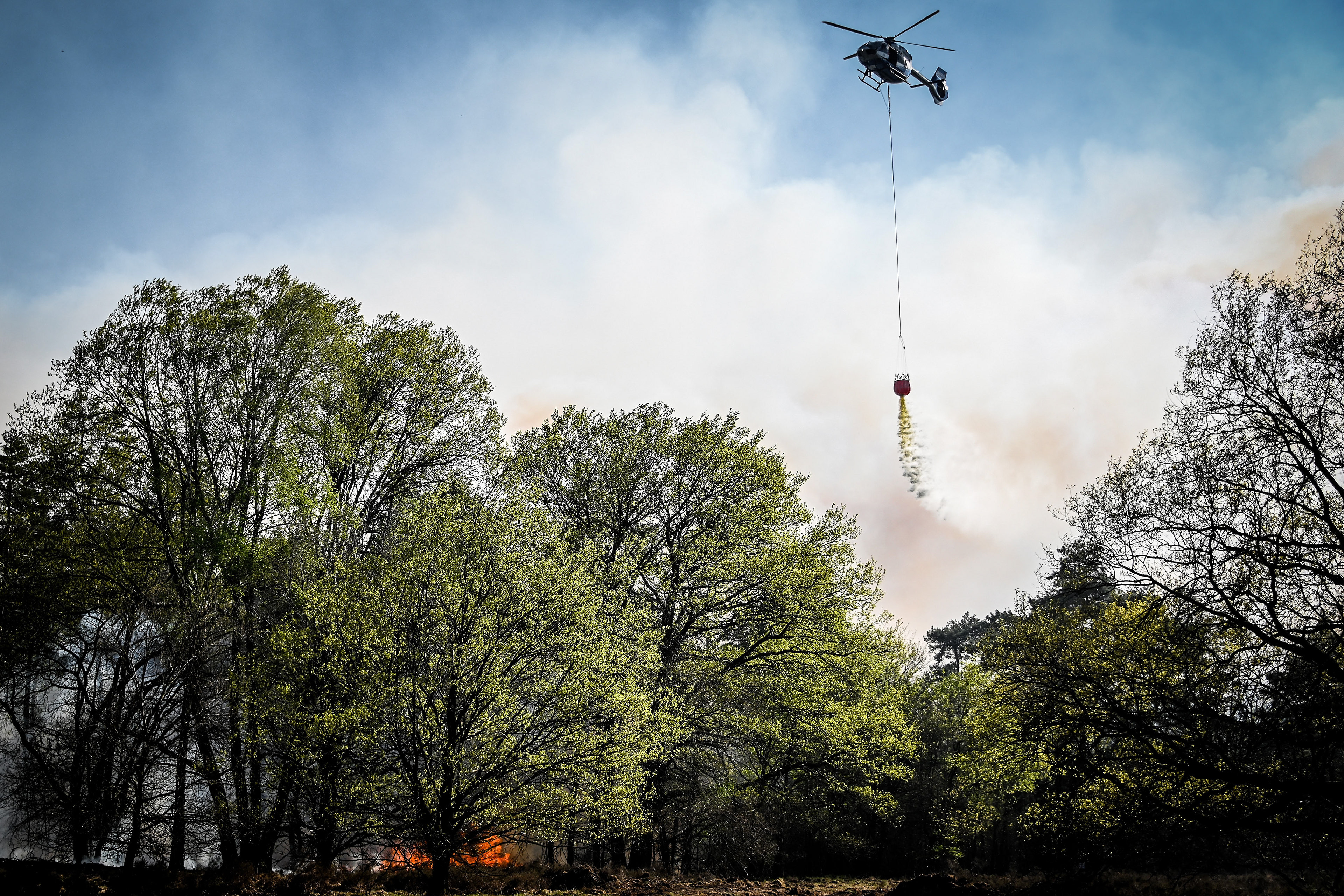 A helicopter throws water over a point of fire during a forest fire at the national park De Meinweg in the German-Dutch border area near Niederkruechten, Germany, 21 April 2020. (Photo by Sascha Steinbach/epa)